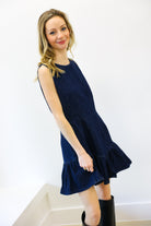 Woman wearing a navy denim blue dress with a white background