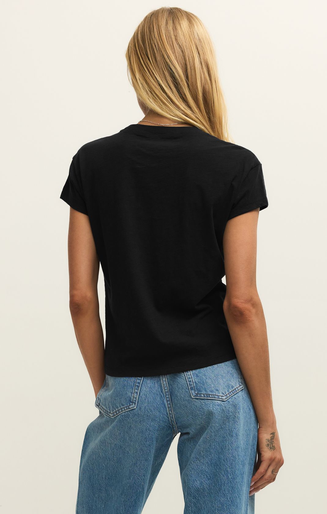 Person wearing a black t-shirt and blue jeans on a plain background