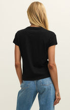 Person wearing a black t-shirt and blue jeans on a plain background