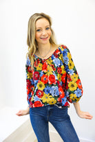 Woman wearing a colorful floral blouse and blue jeans on a white background