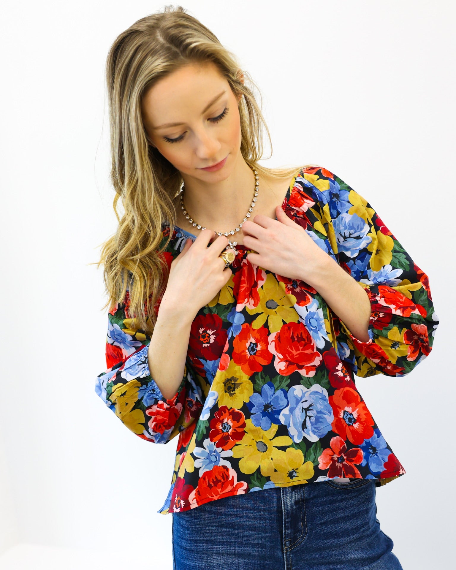 Woman wearing a colorful floral blouse against a white background