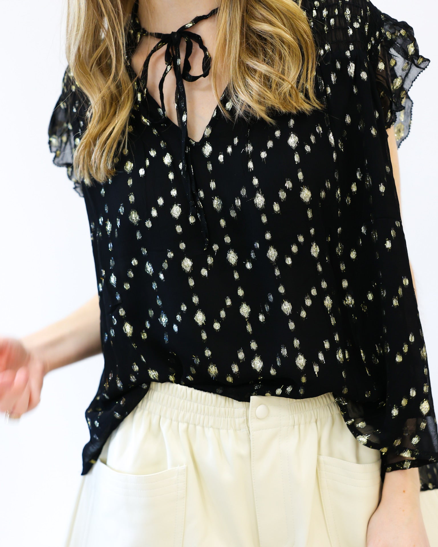 Black floral blouse with white pants on a plain background