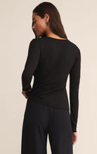 Person wearing a black long-sleeve top and pants on a beige background