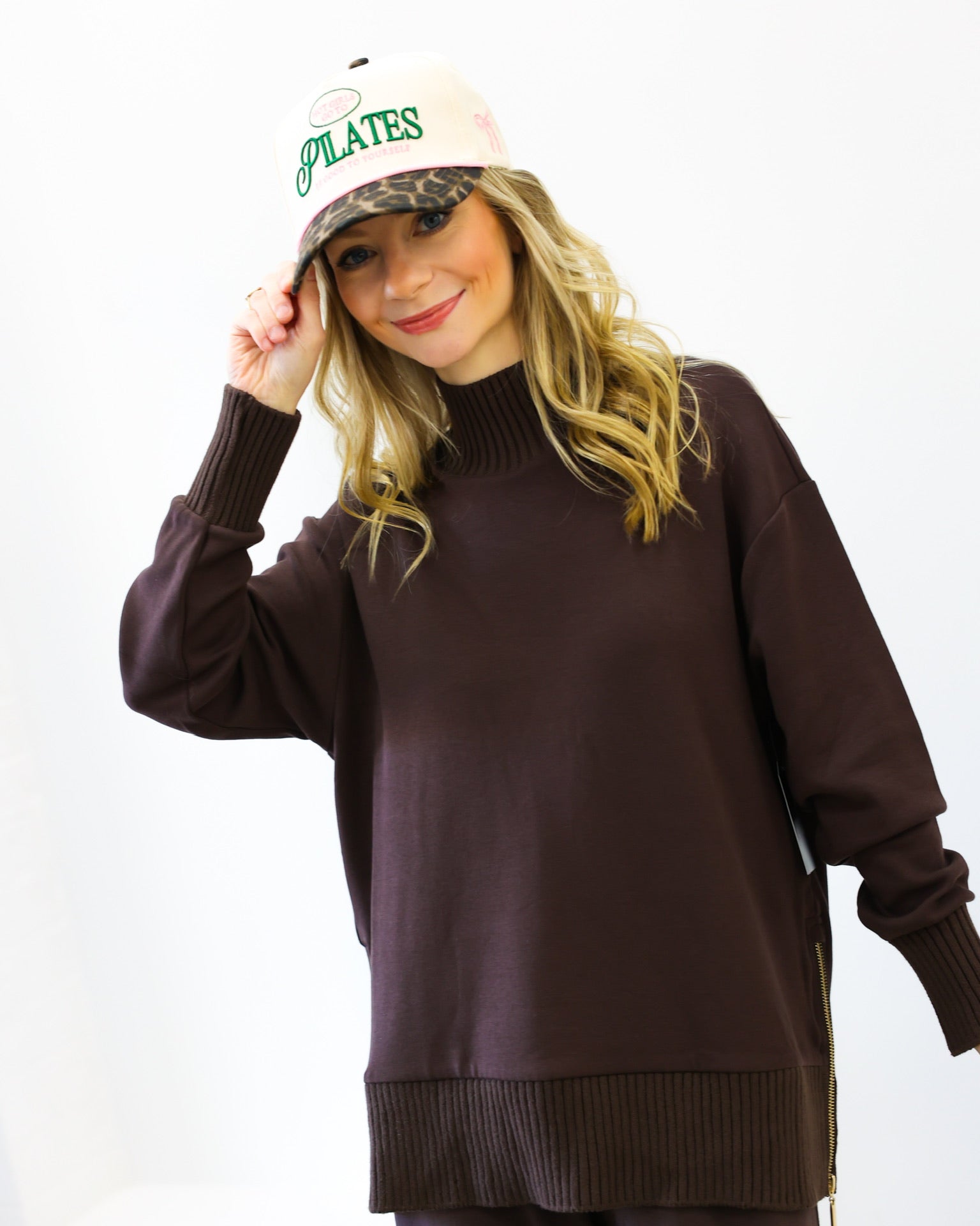 Person wearing a brown sweater and white cap with text on a white background