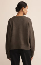 Woman wearing a brown sweater from behind on a beige background