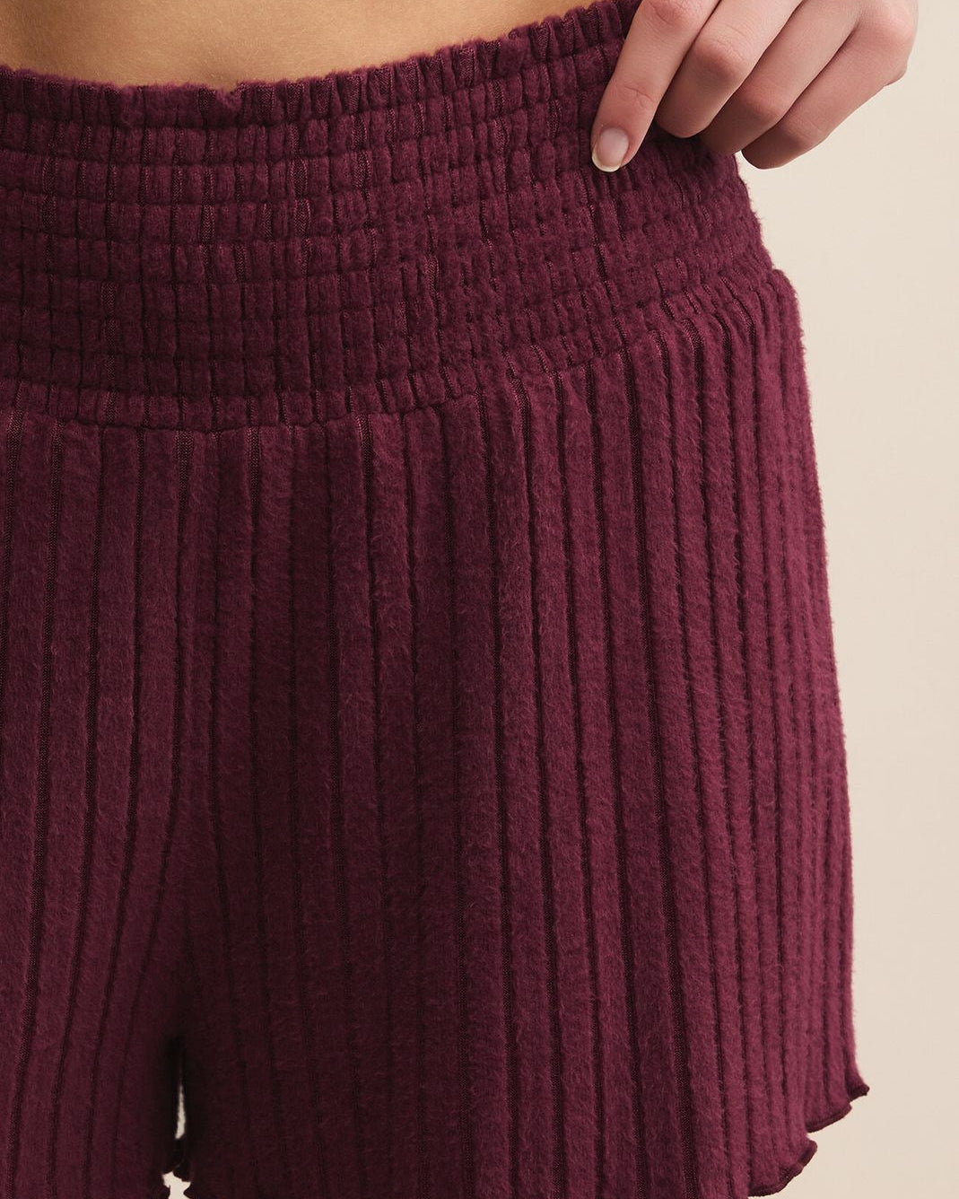 Maroon ribbed shorts worn by a person on a beige background