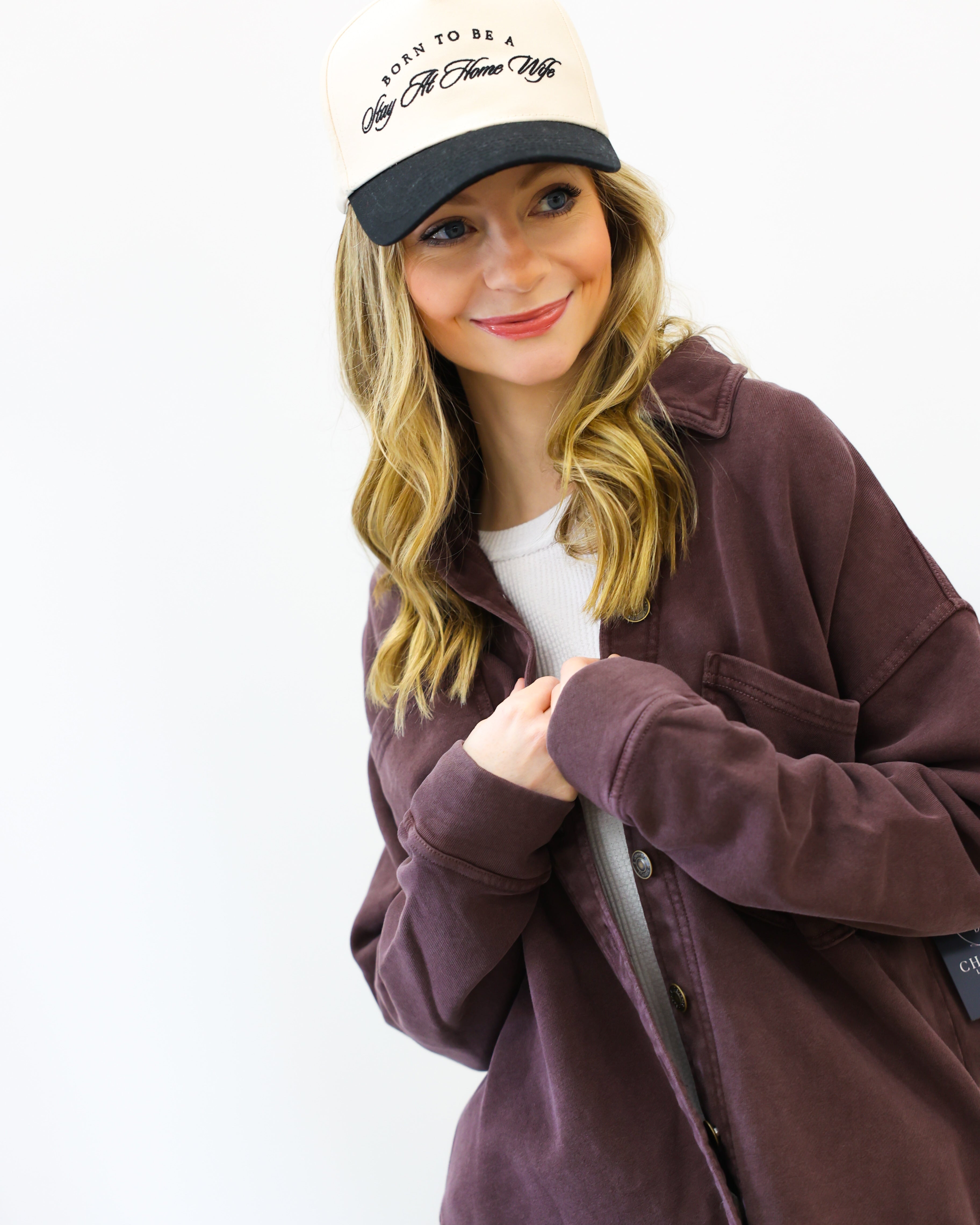 Person wearing a brown jacket and beige cap with text on a white background
