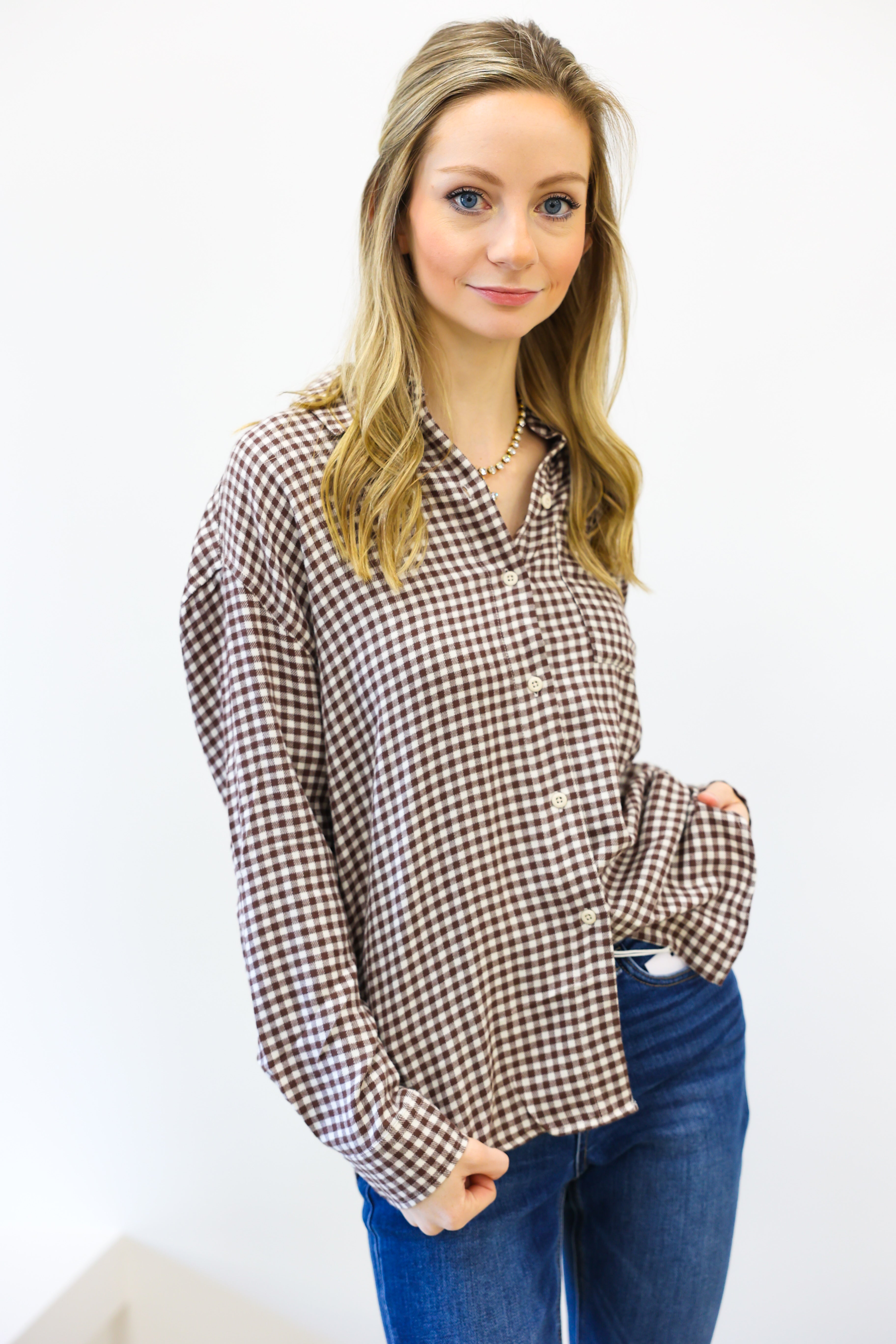 Woman wearing a checkered shirt and jeans against a white background