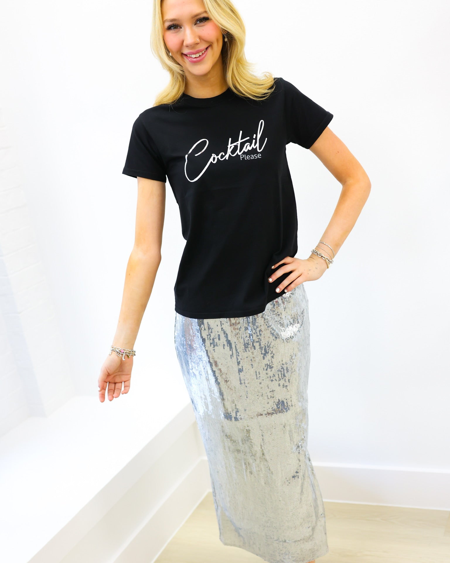 Woman wearing a black t-shirt with 'Cocktail' text and a patterned skirt on a white background