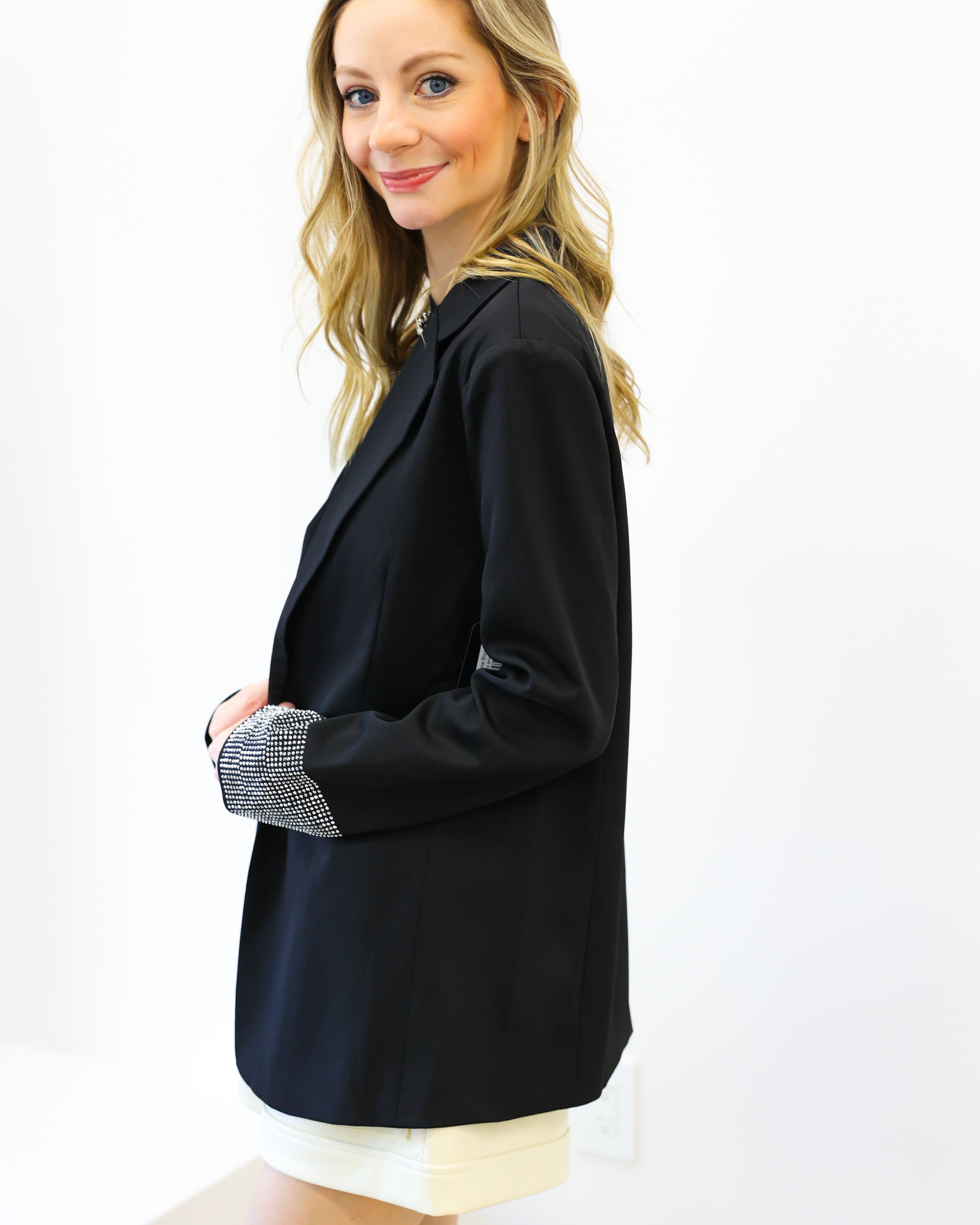 Woman wearing a black blazer over a white top on a white background