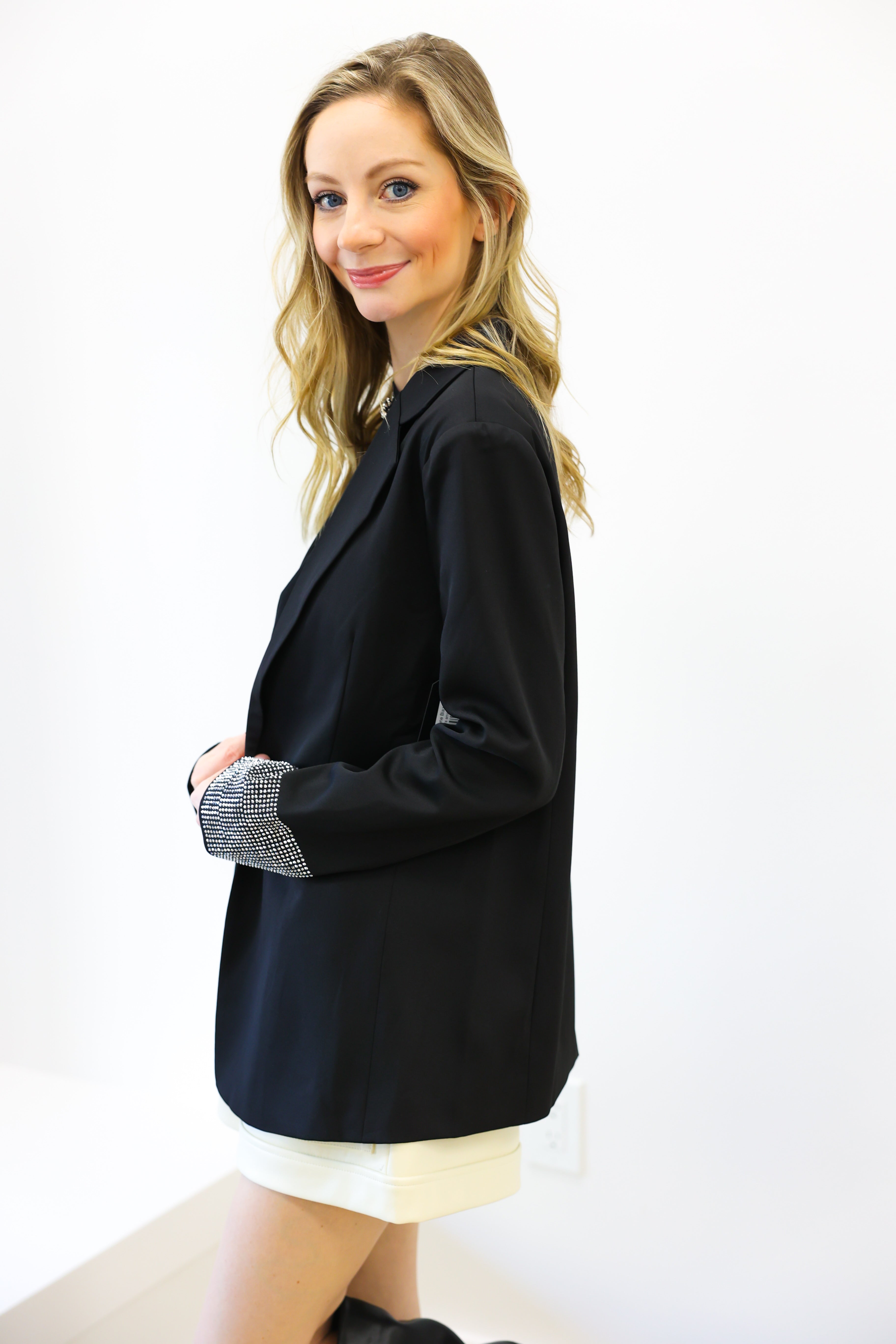 Woman wearing a black blazer over a white top on a white background