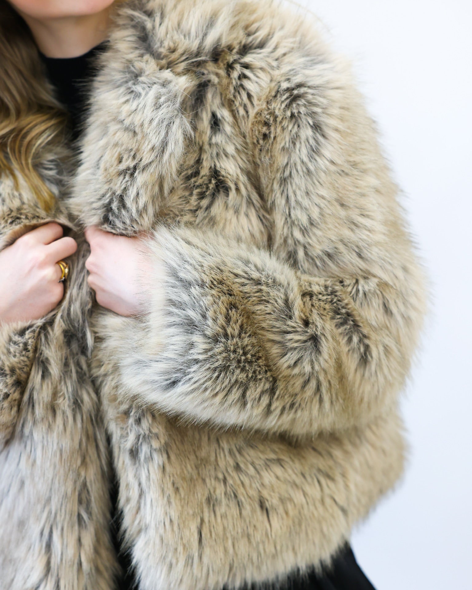 Close-up of a person wearing a fur coat with a neutral background