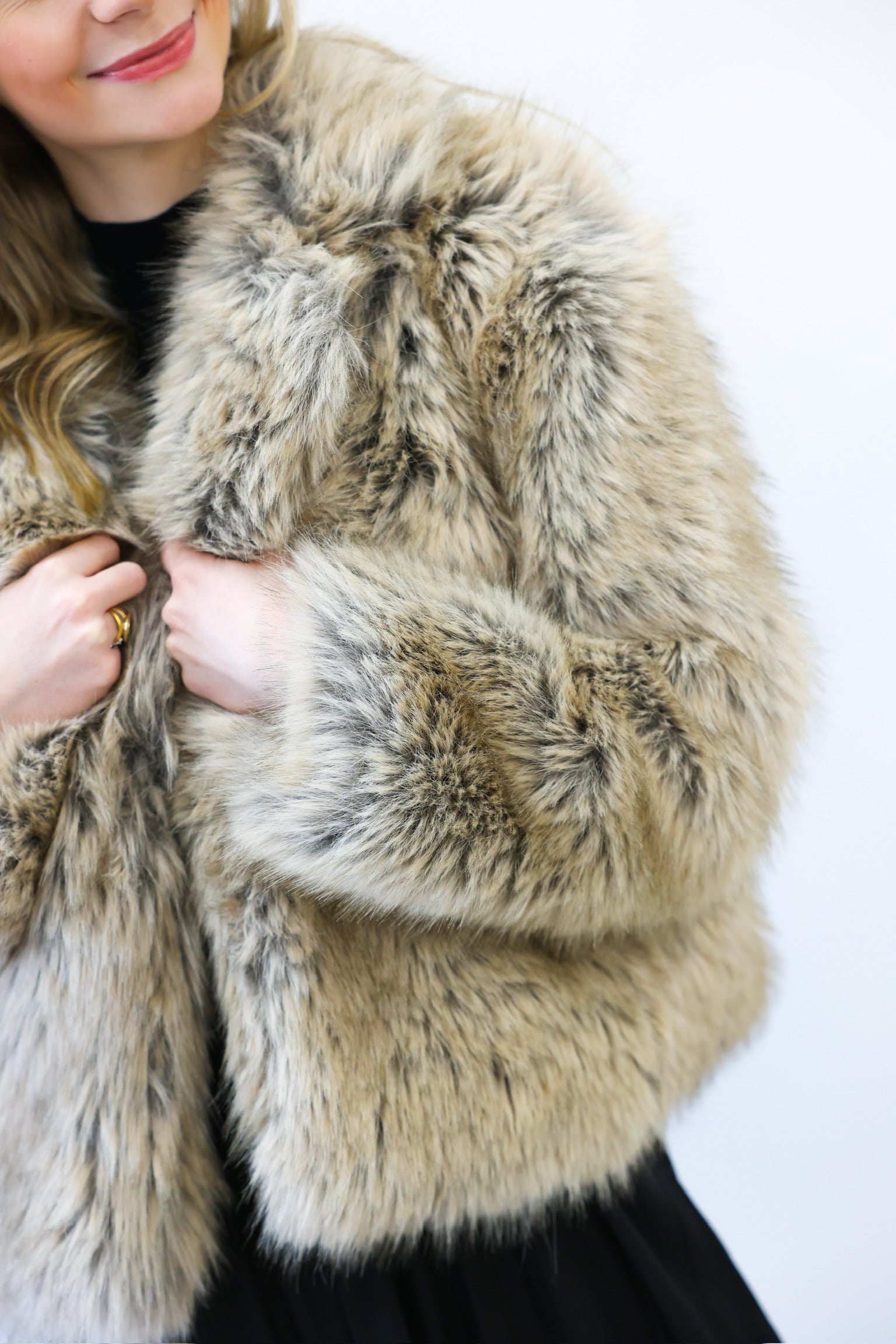 Close-up of a person wearing a fur coat with a neutral background