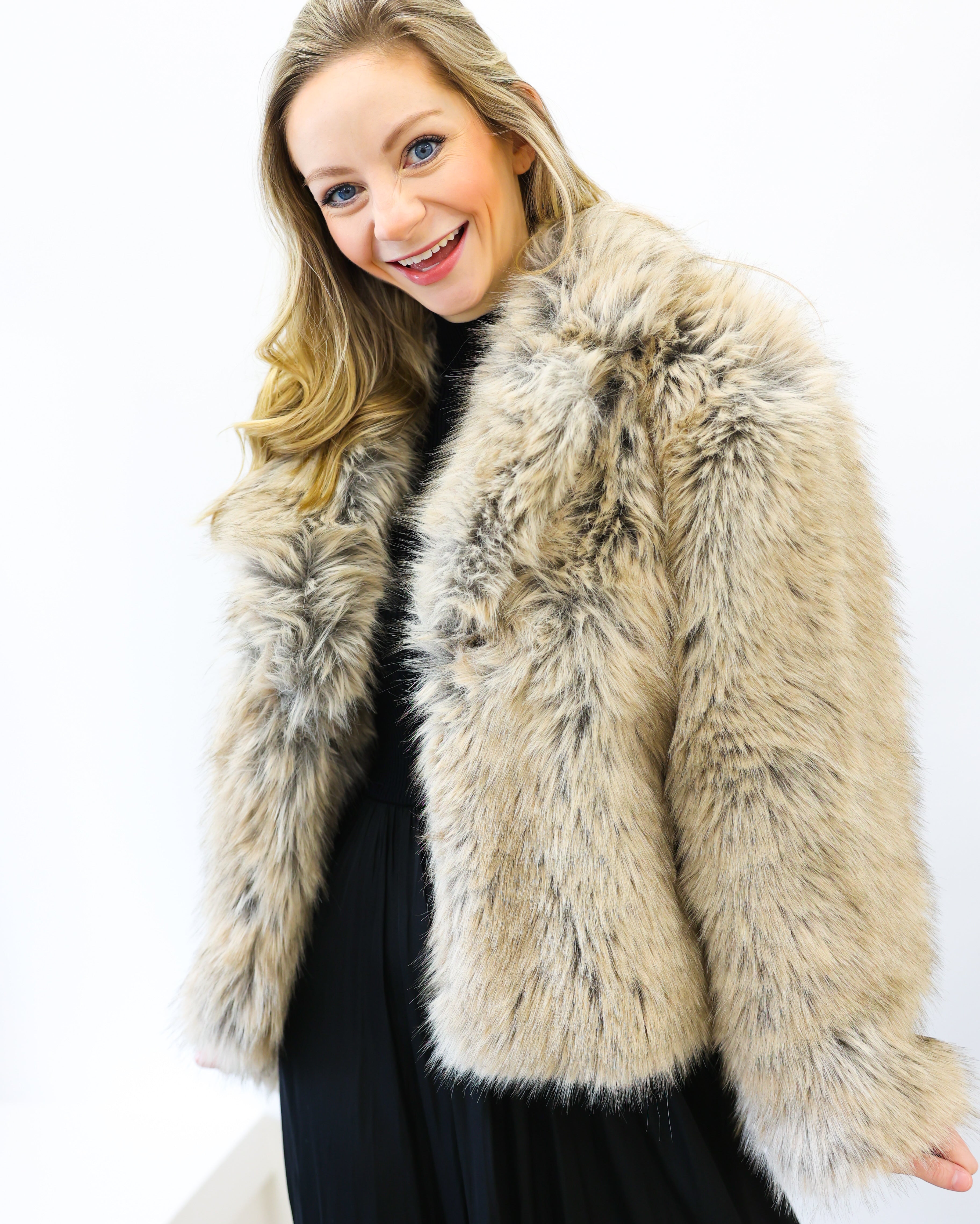 Woman wearing a beige fur coat against a white background