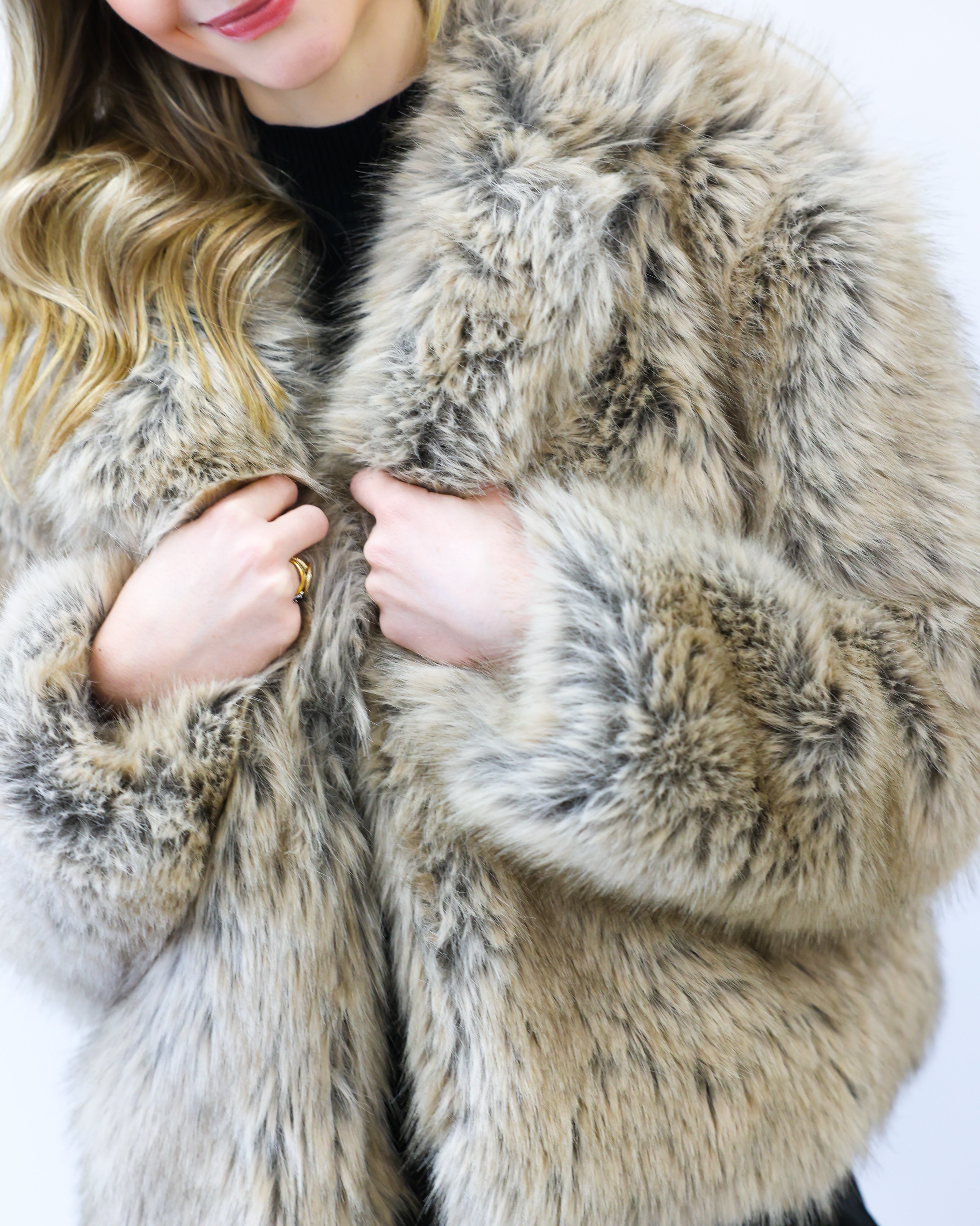 Person wearing a fluffy beige coat against a white background