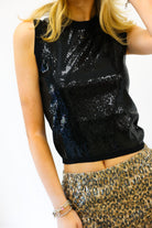 Person wearing a black sequin top and gold skirt on a white background