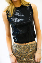 Person wearing a black sequin top and gold sequin skirt on a white background