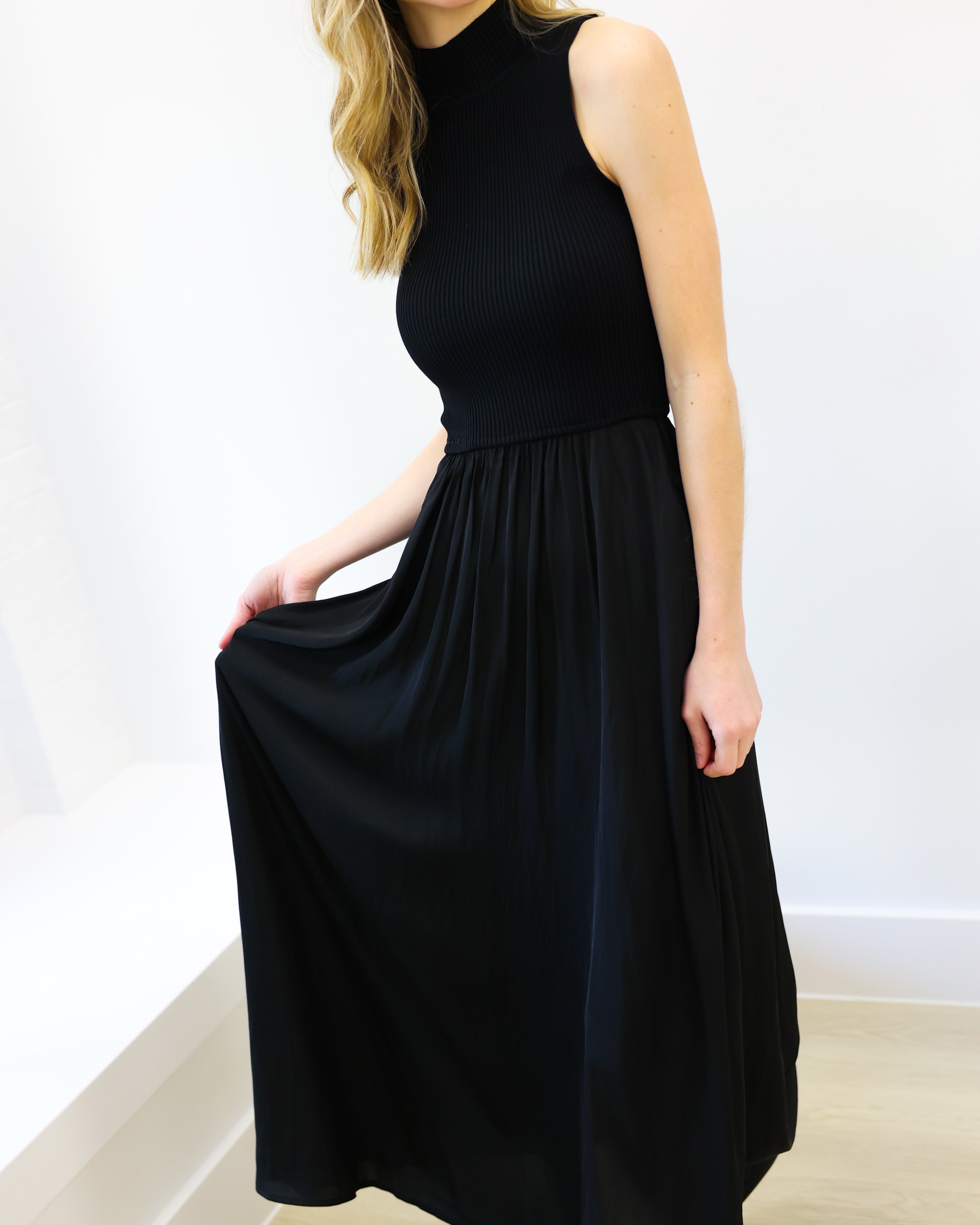 Woman wearing a black sleeveless dress against a white background
