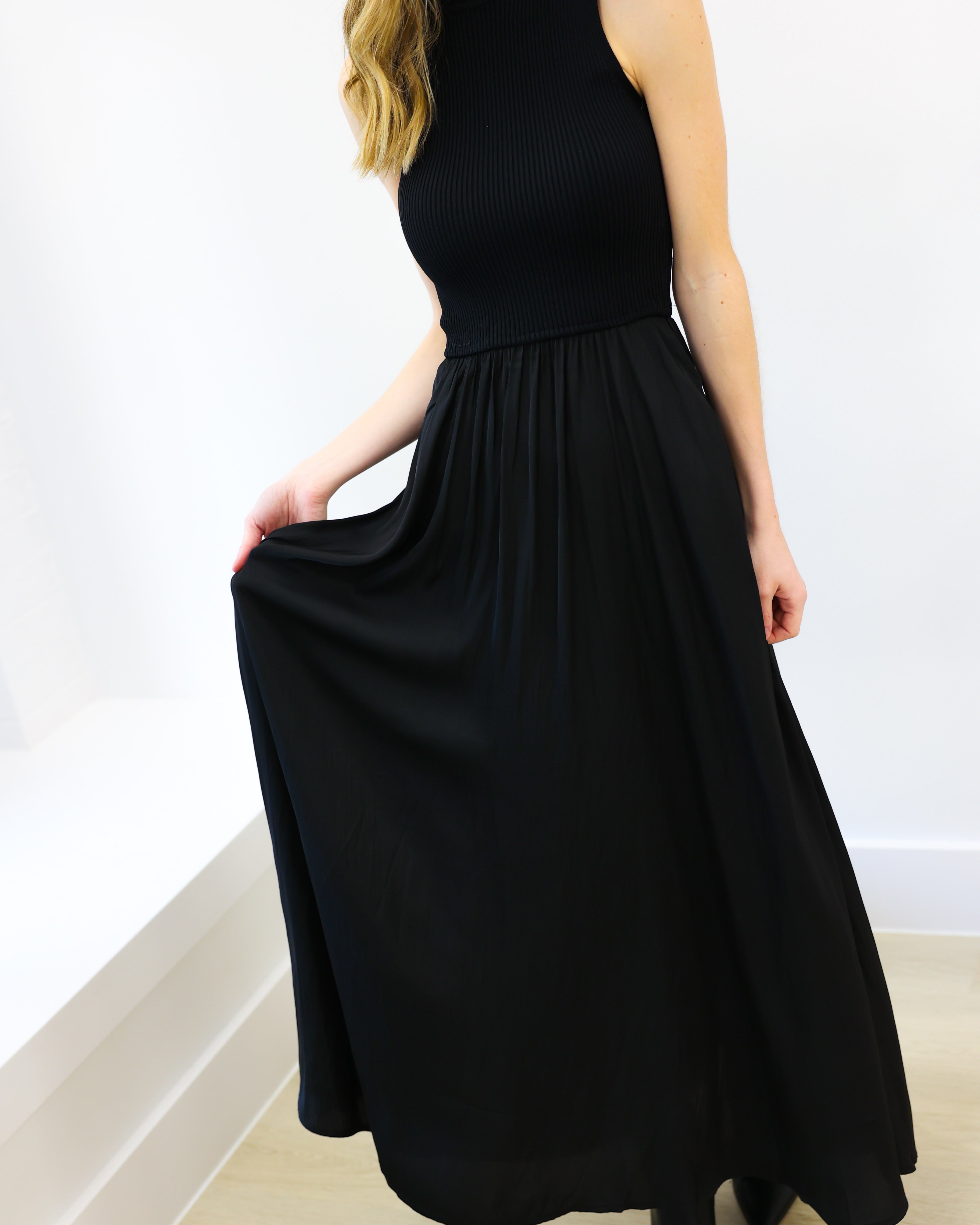 Woman wearing a black sleeveless dress against a white background
