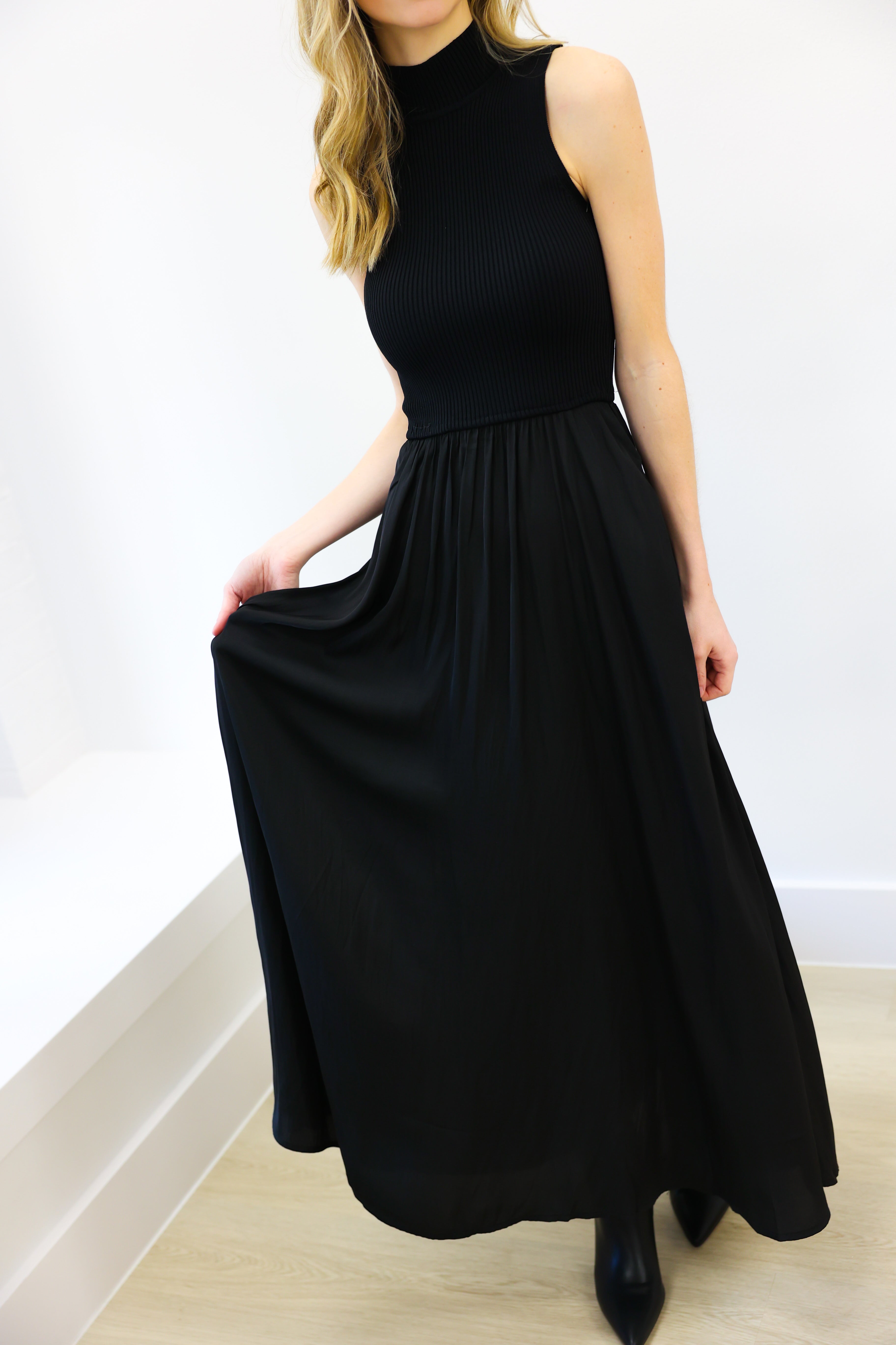 Woman wearing a black sleeveless dress against a white background