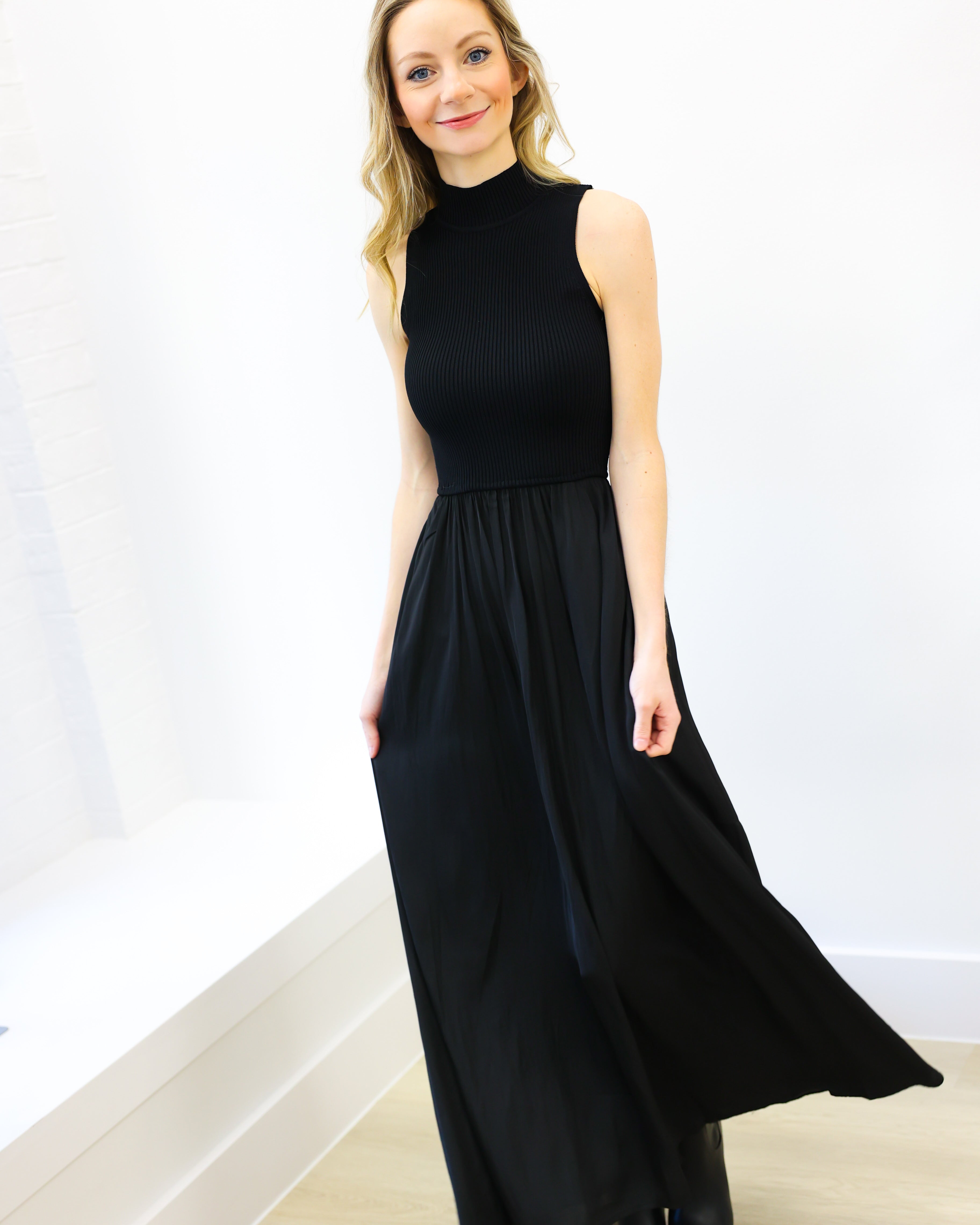 Woman wearing a black sleeveless dress against a white background