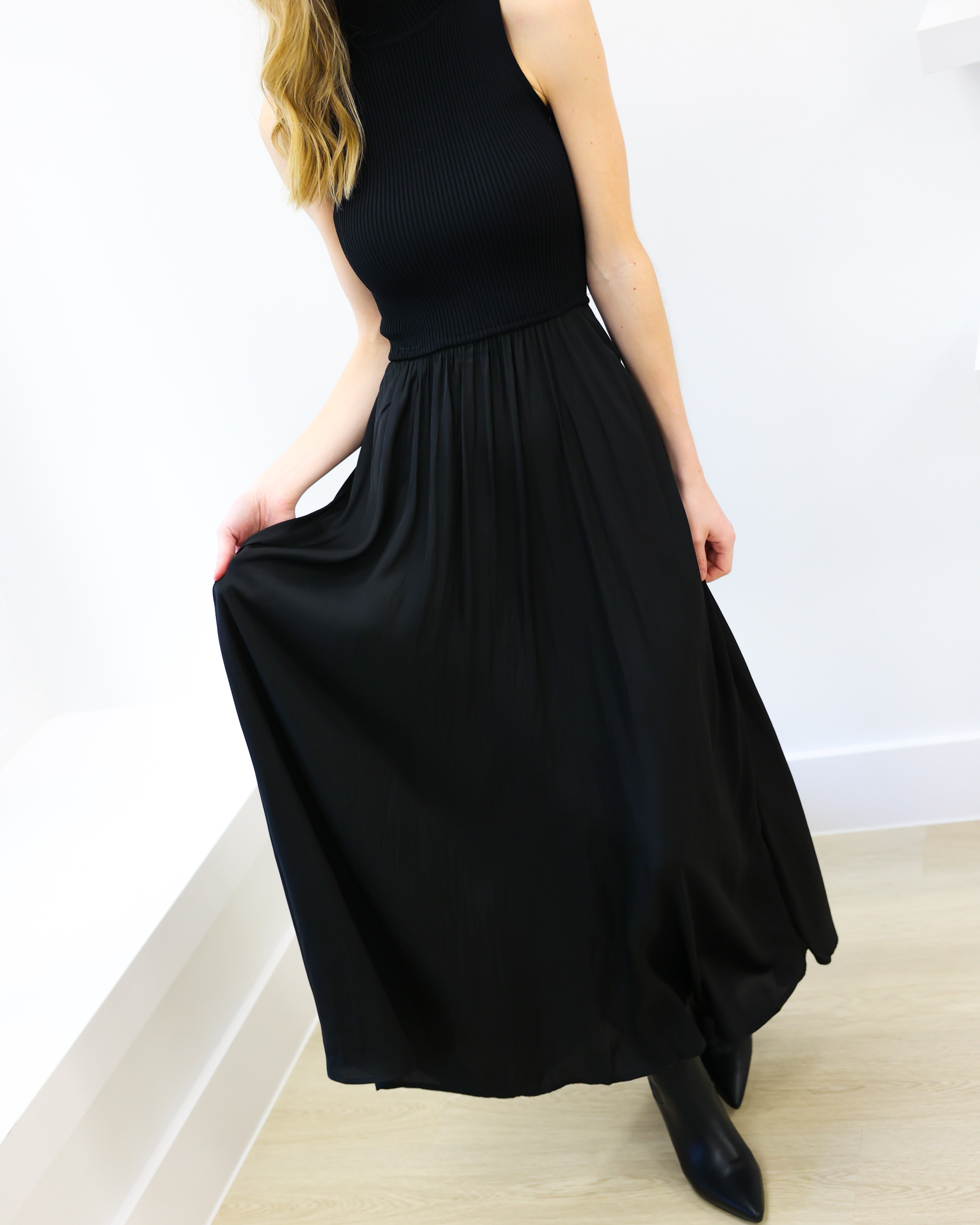 Woman wearing a black sleeveless dress in a minimal indoor setting