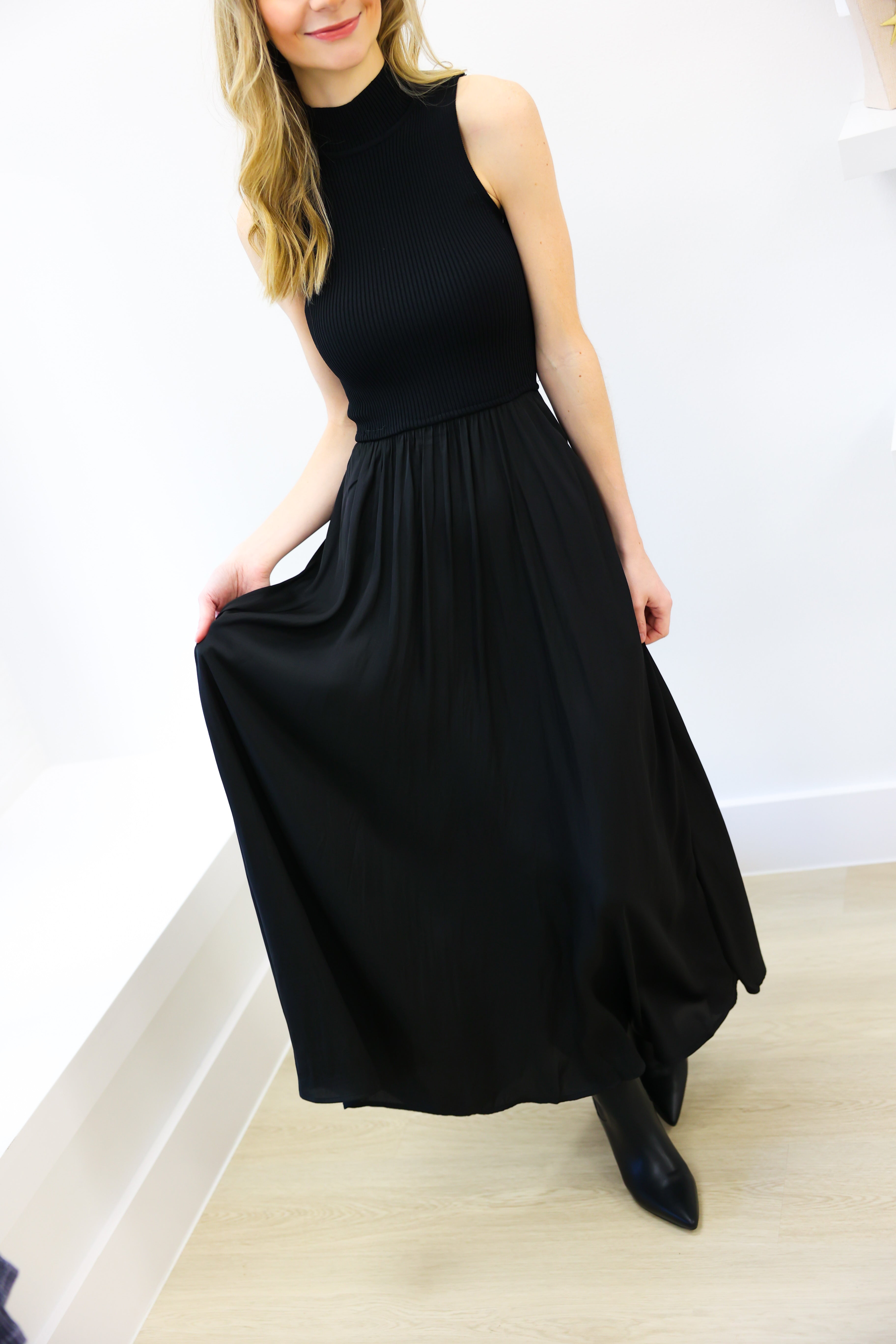 Woman wearing a black sleeveless dress in a minimal indoor setting
