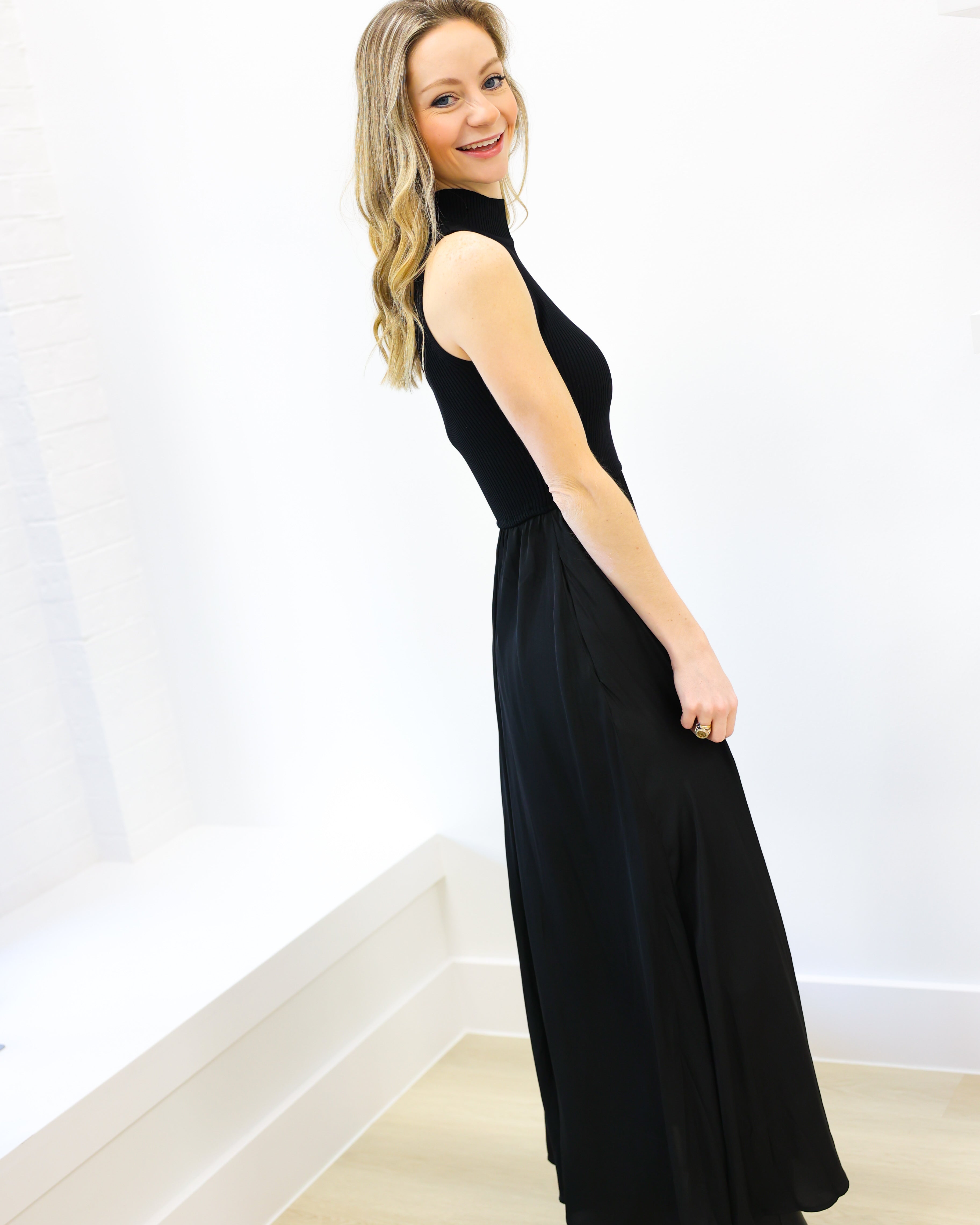 Woman wearing a black sleeveless dress against a white background