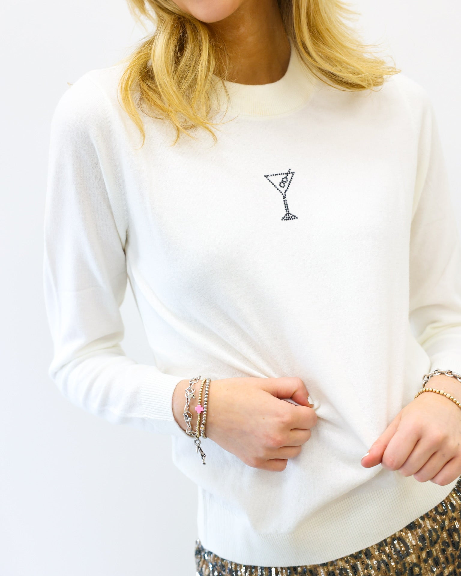 Person wearing a white sweatshirt with a small black design on a plain background
