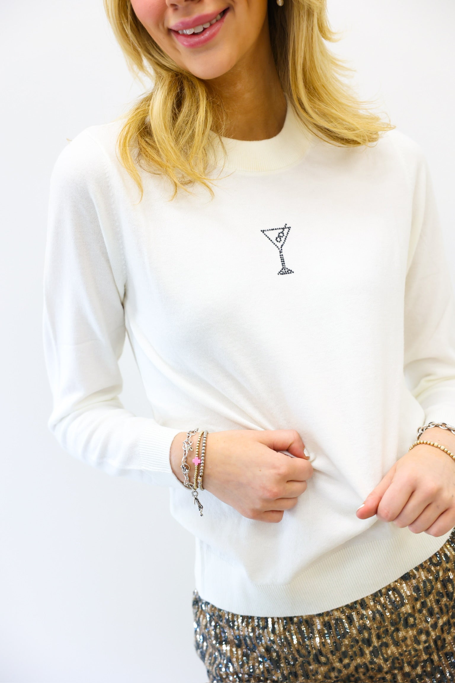 Person wearing a white sweatshirt with a small black design on a plain background