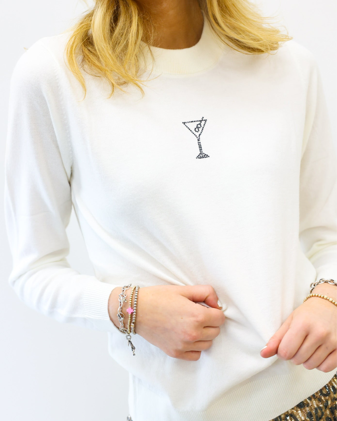White sweatshirt with a small design on the chest, worn by a person.
