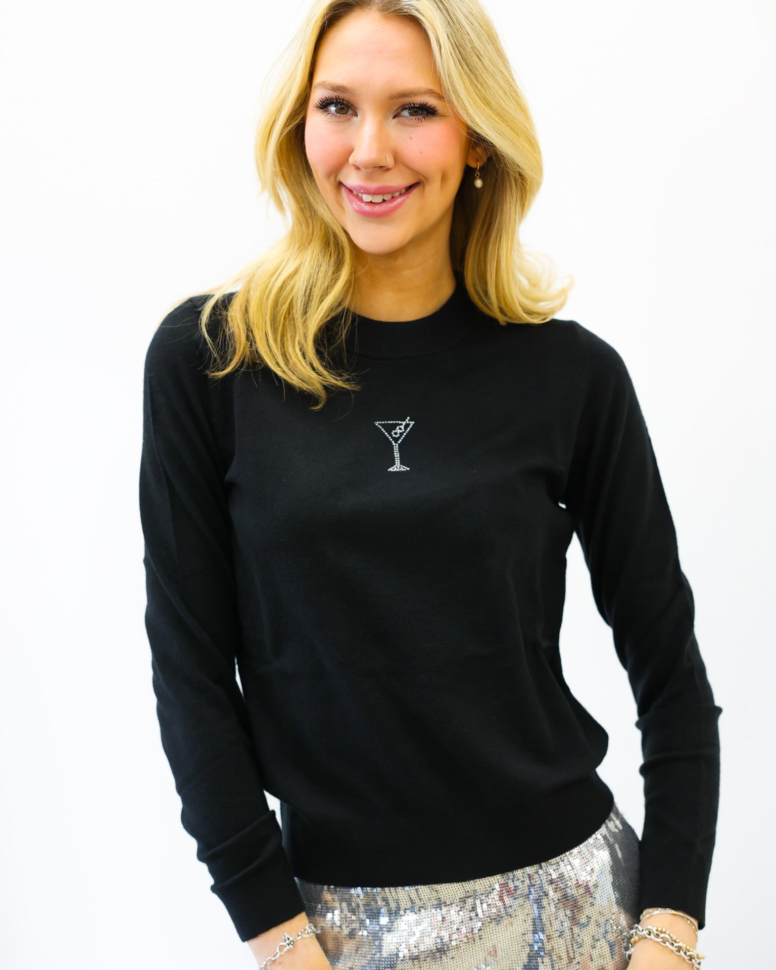 Woman wearing a black sweater with a martini glass design on a white background
