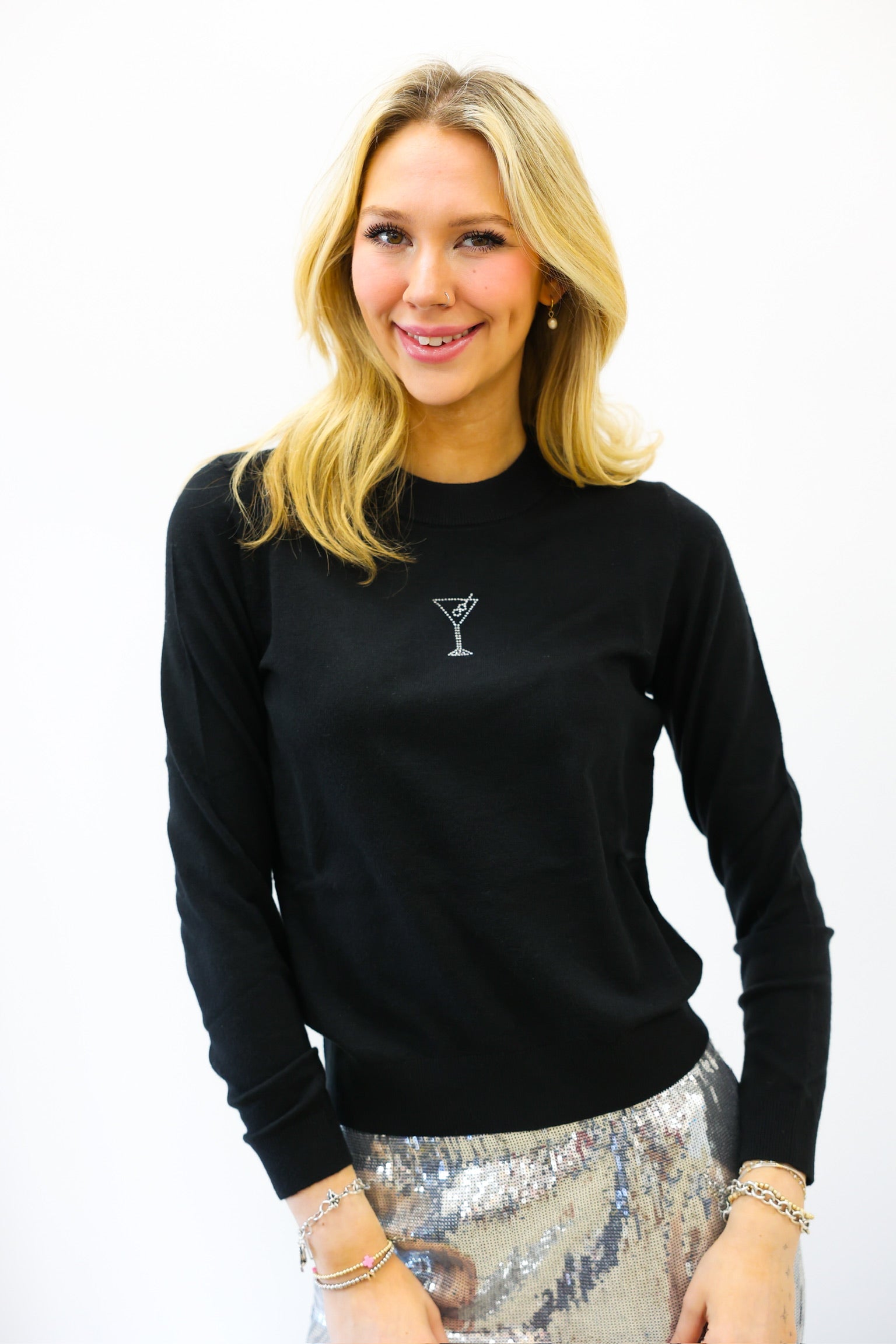 Woman wearing a black sweater with a martini glass design on a white background