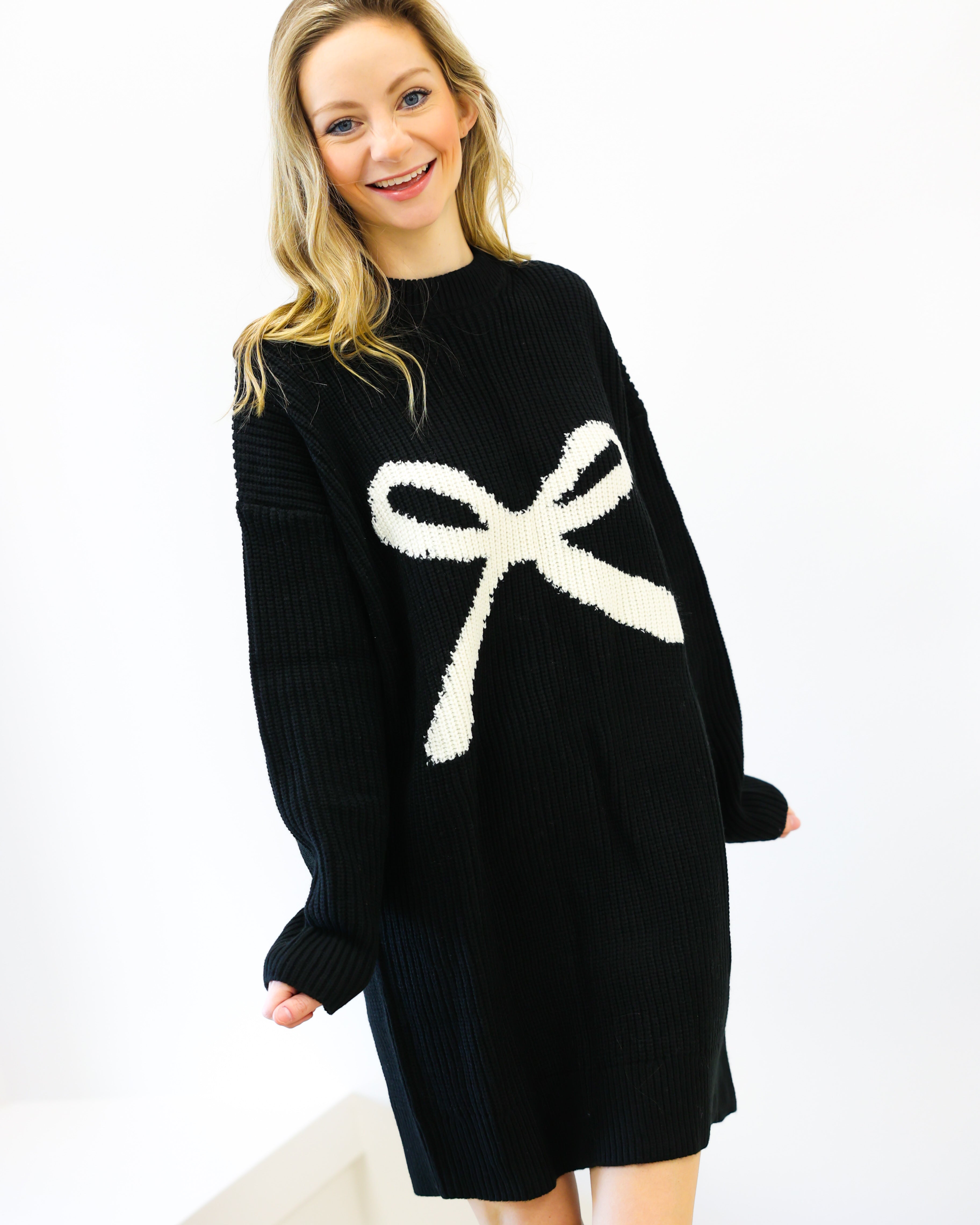 Woman wearing a black sweater dress with a white bow design on a white background