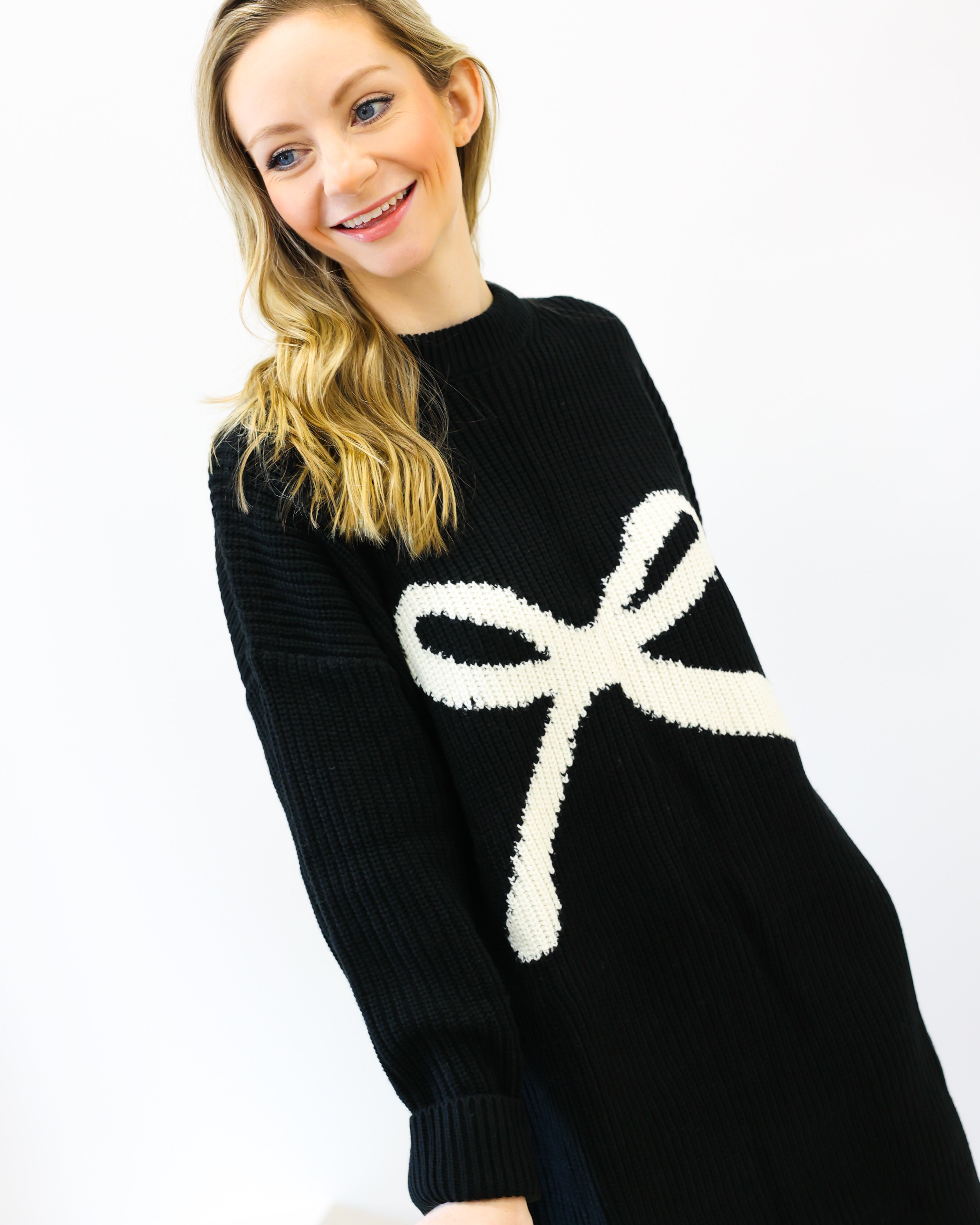 Woman wearing a black sweater with a white bow design on a white background