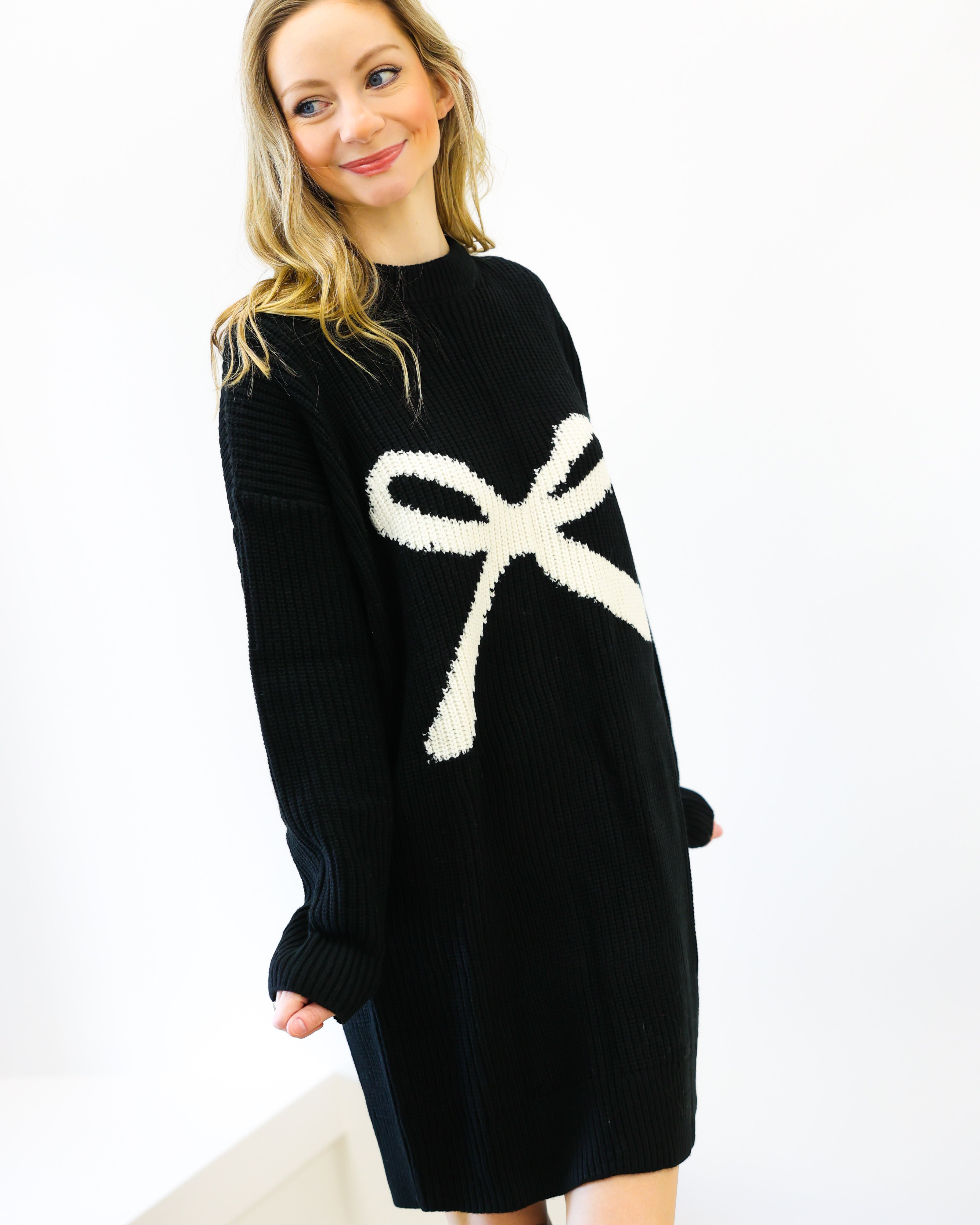 Woman wearing a black sweater with a white bow design on a white background