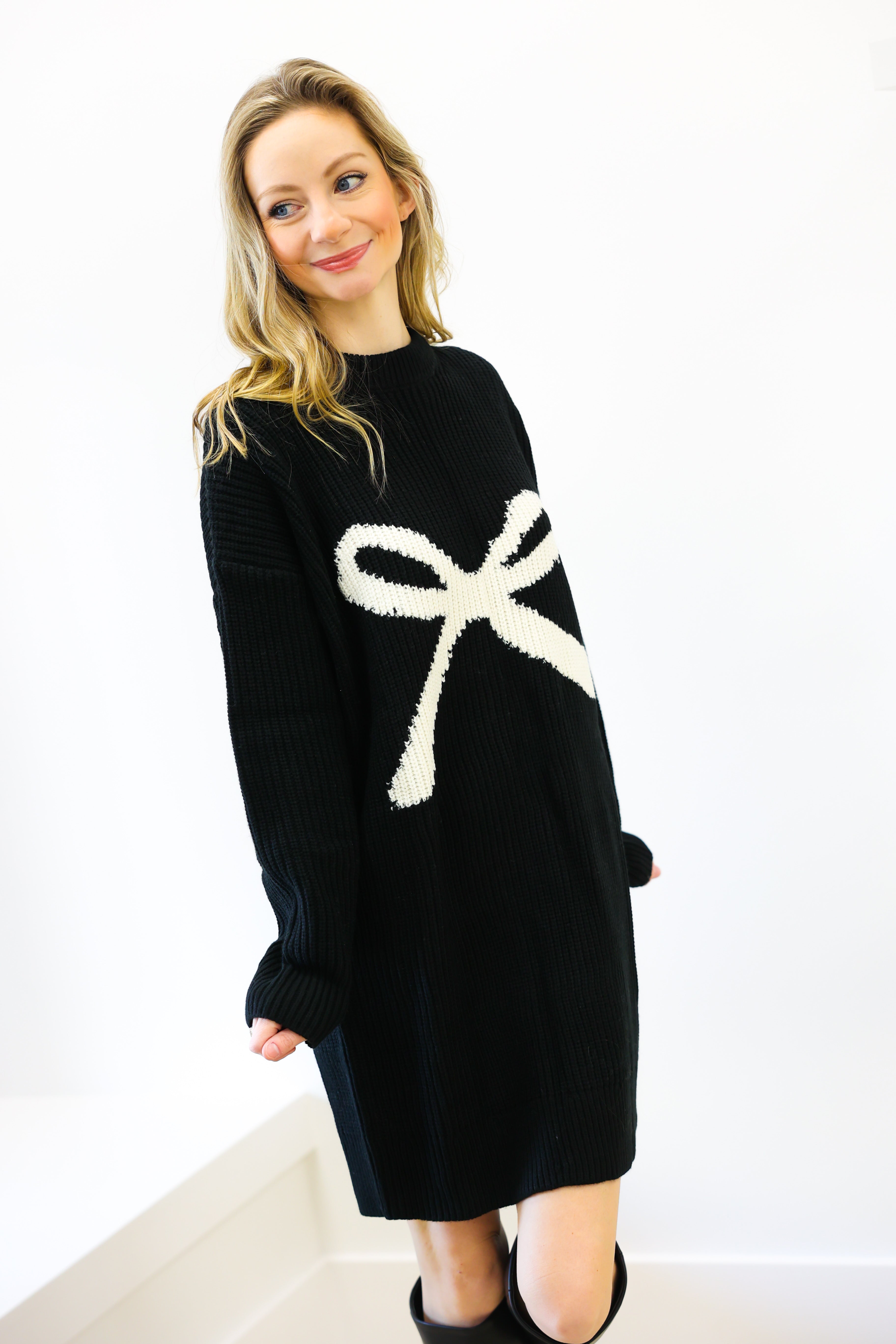Woman wearing a black sweater with a white bow design on a white background