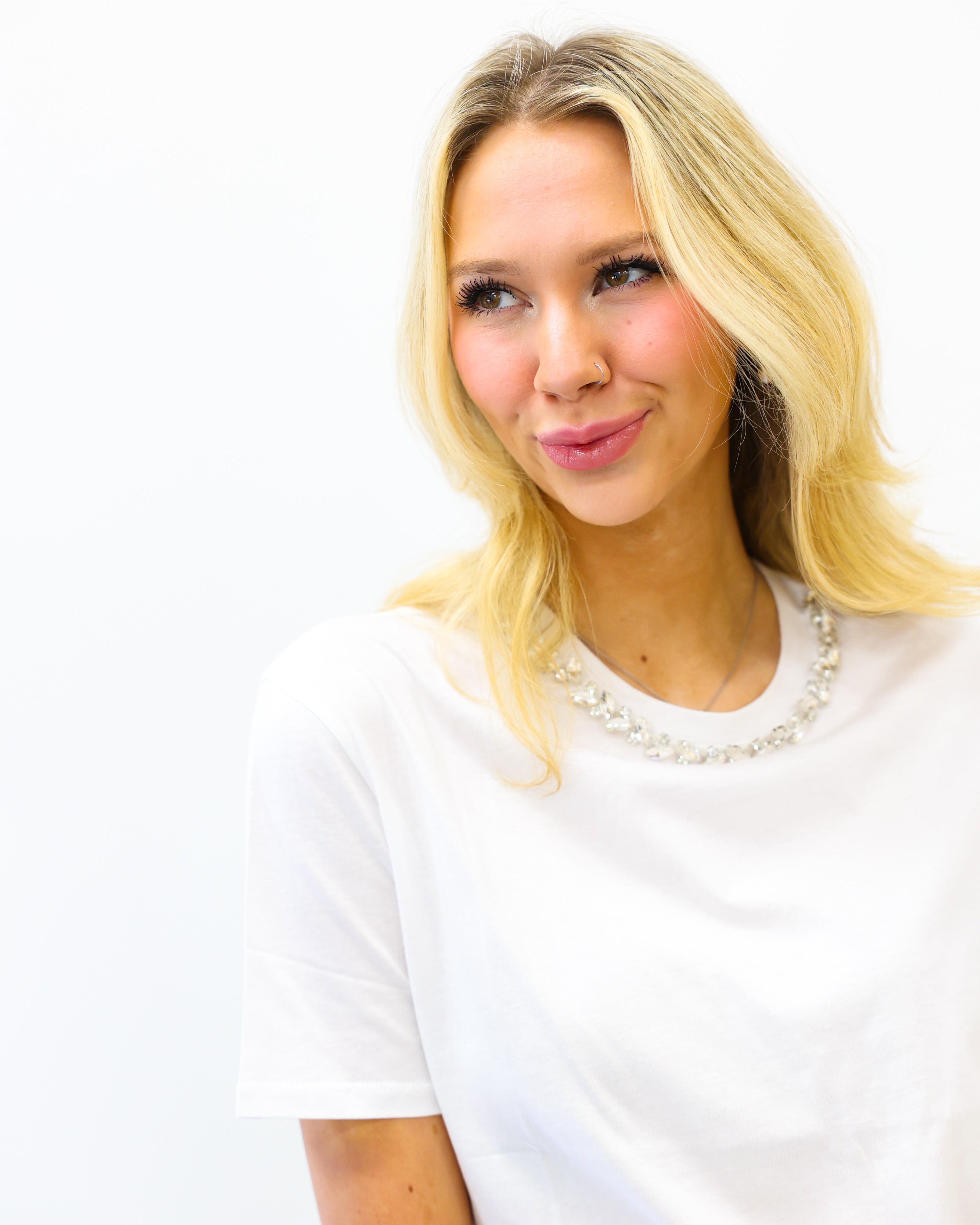 Woman with blonde hair wearing a white shirt against a white background