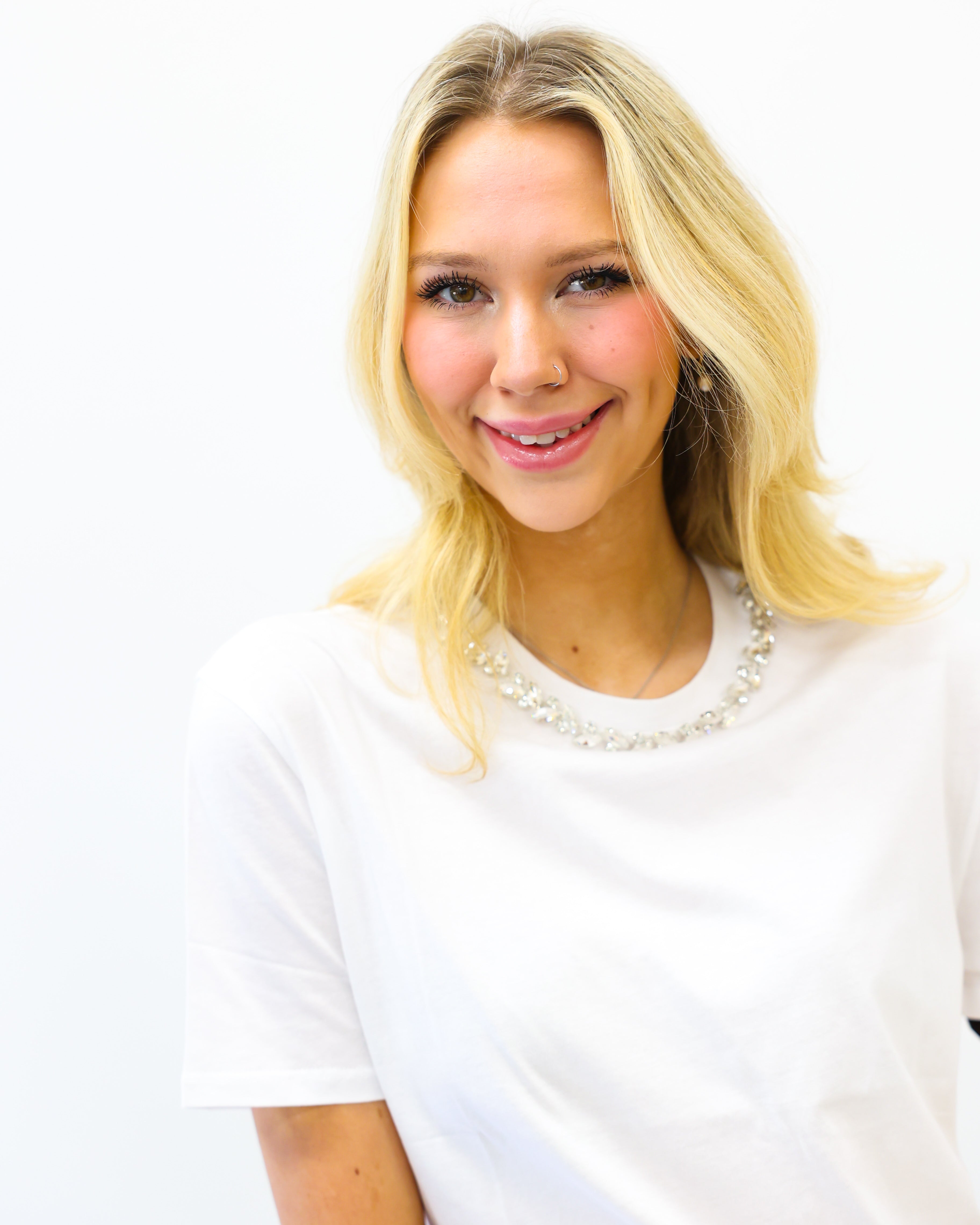 Woman with blonde hair wearing a white shirt against a white background