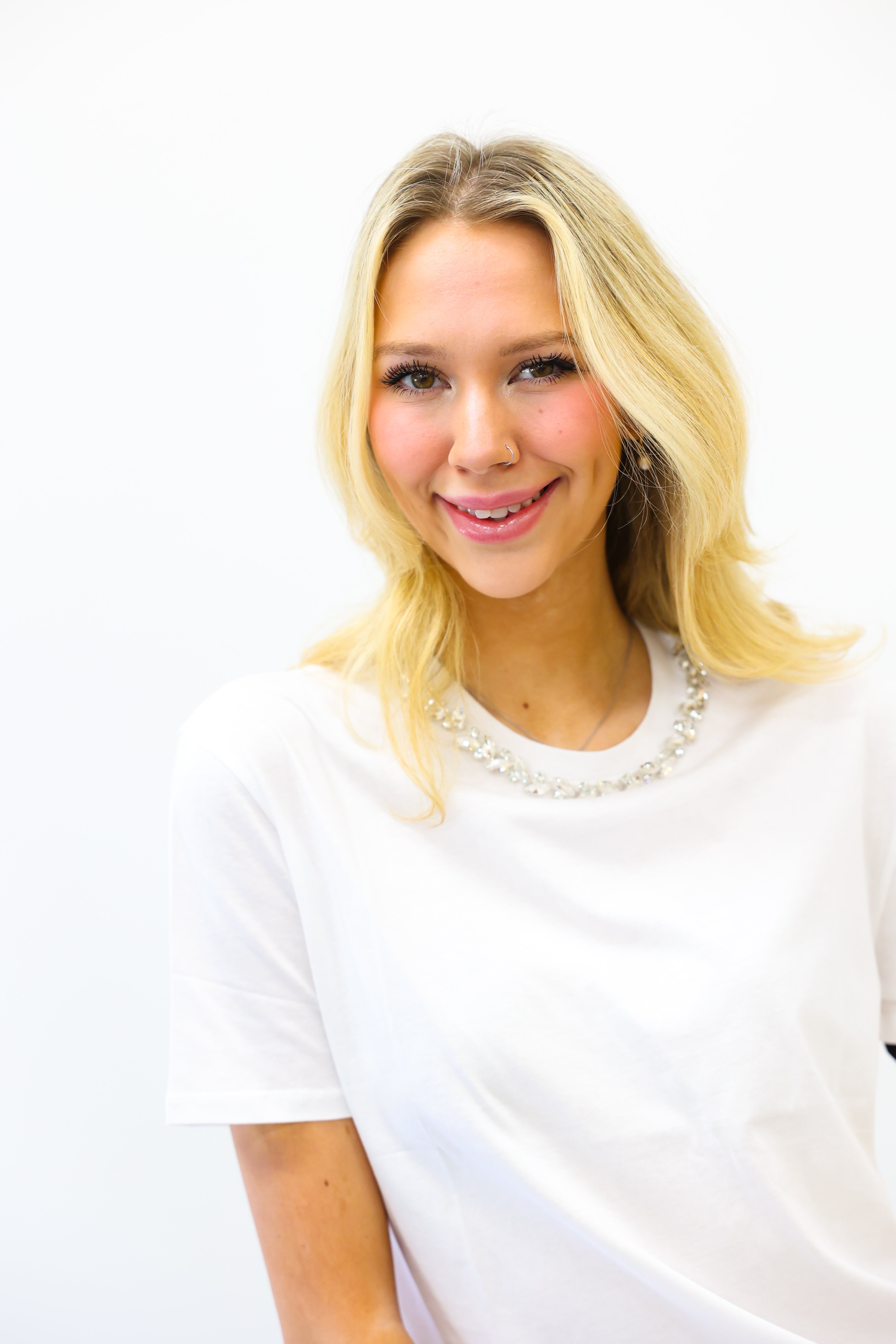 Woman with blonde hair wearing a white shirt against a white background