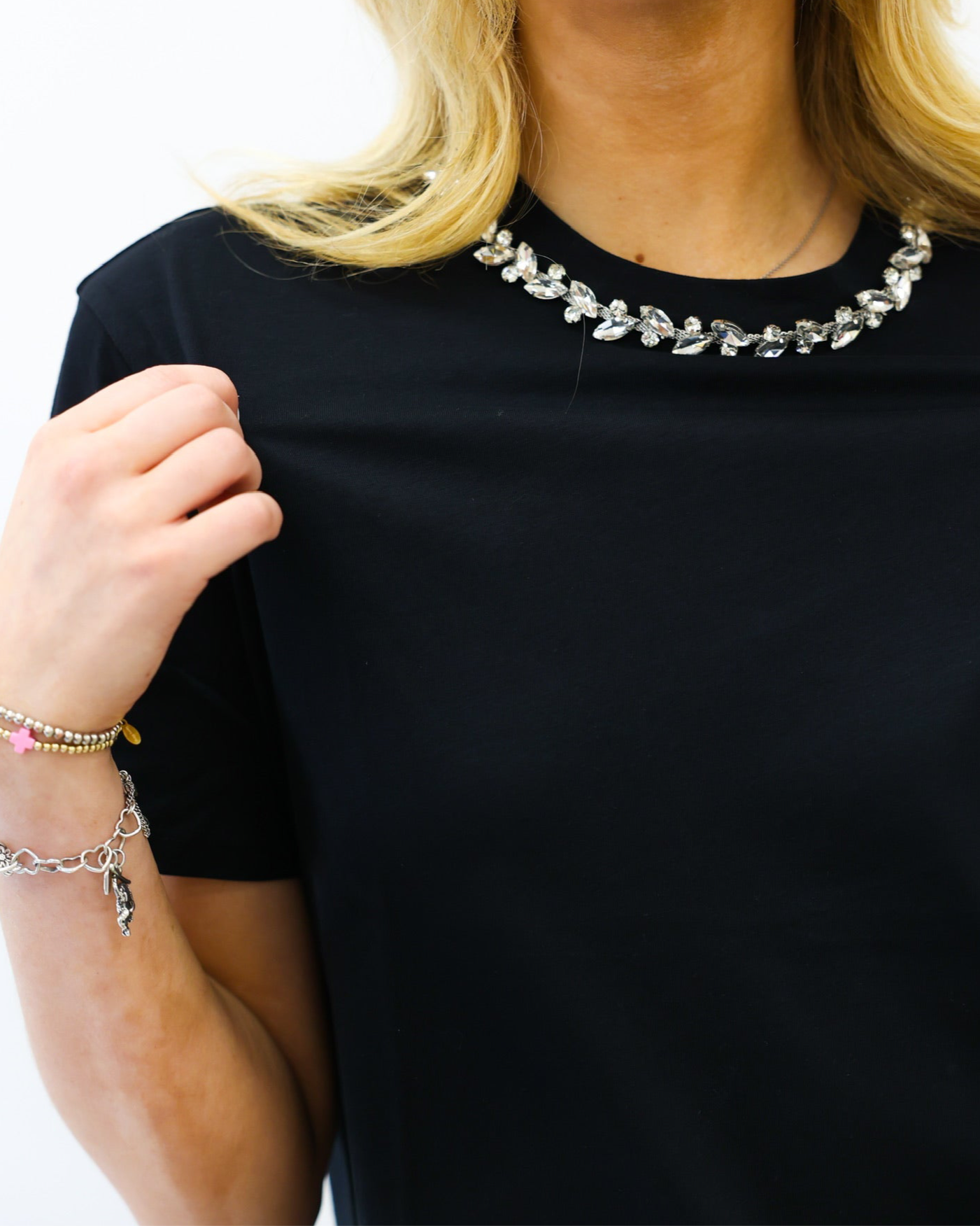 Person wearing a black shirt with a decorative necklace on a white background