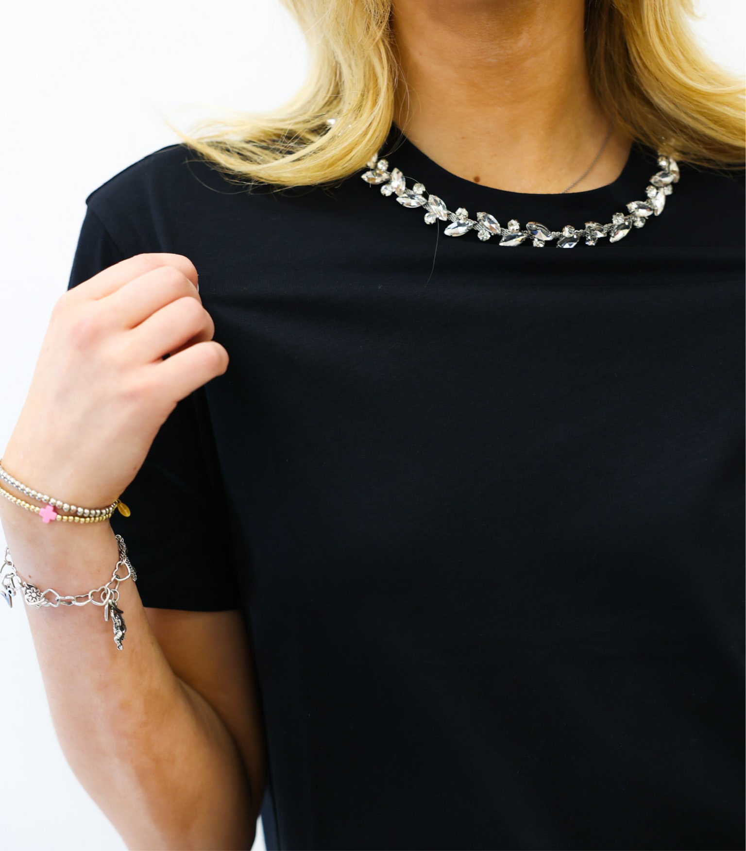Person wearing a black shirt with a decorative necklace on a white background