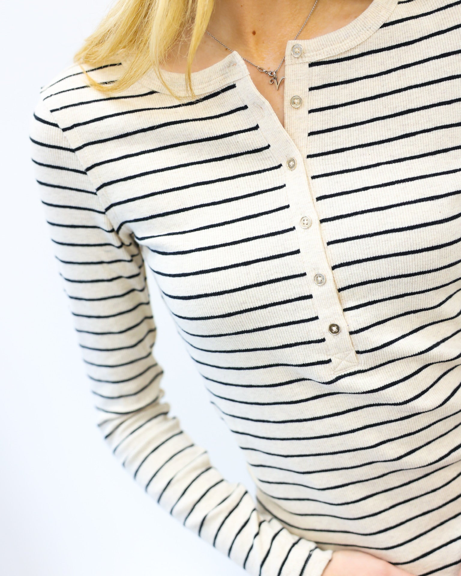 Close-up of a person wearing a black and white striped long-sleeve shirt with a plain background.