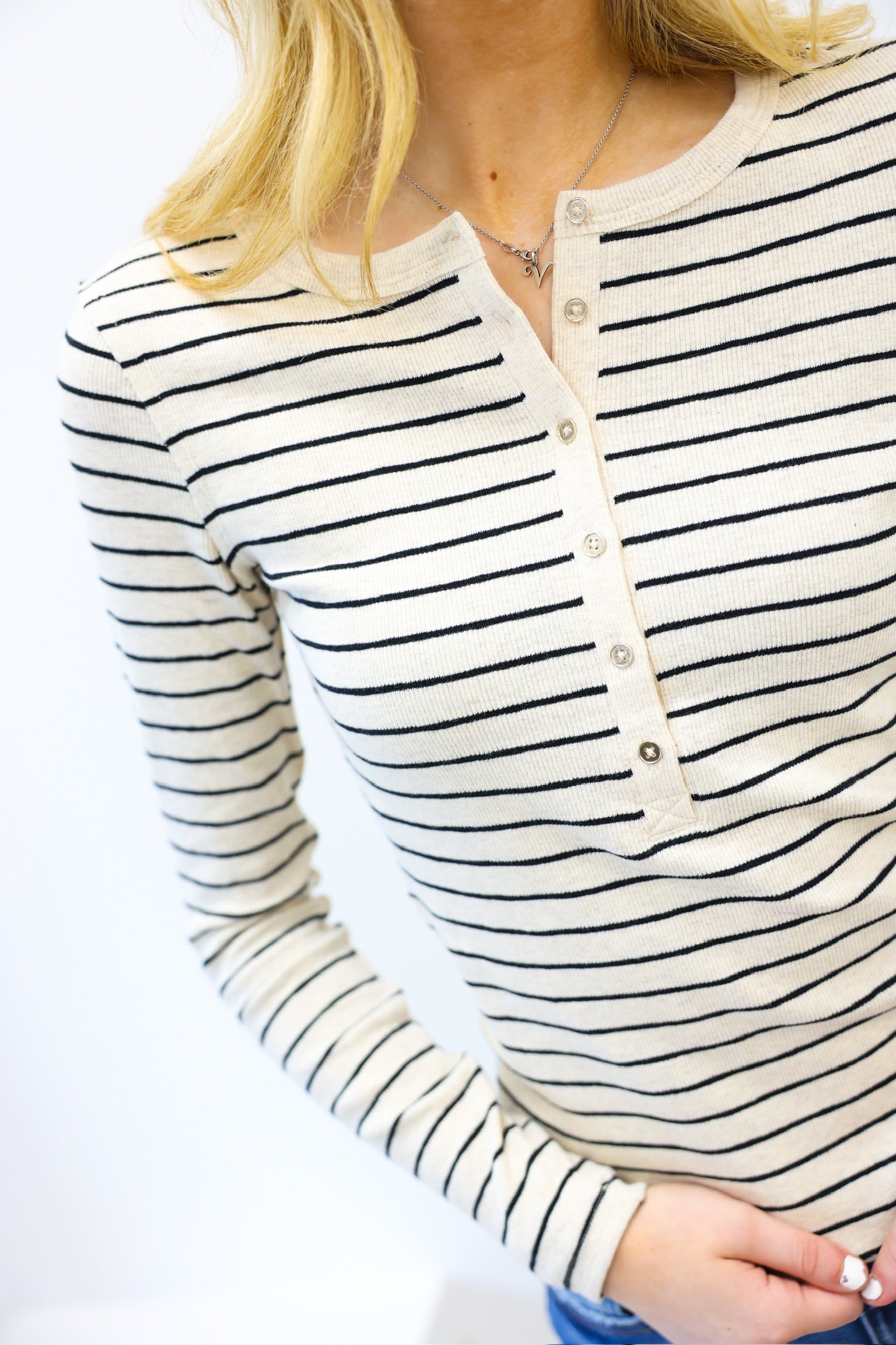 Close-up of a person wearing a black and white striped long-sleeve shirt with a plain background.