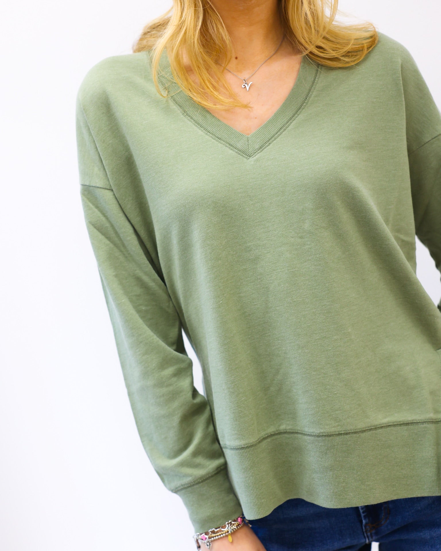 Person wearing a green sweater with a plain background
