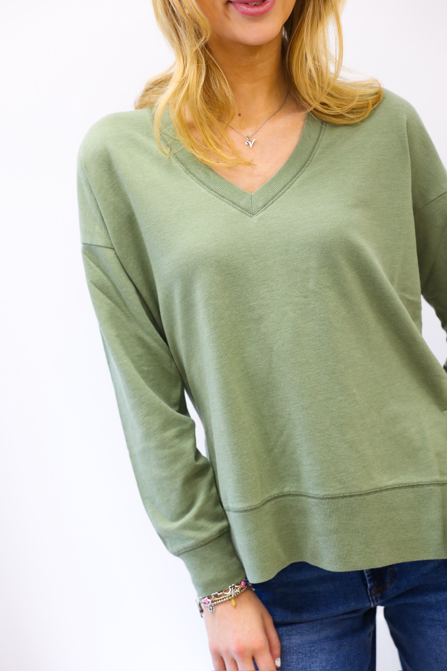 Person wearing a green sweater with a plain background