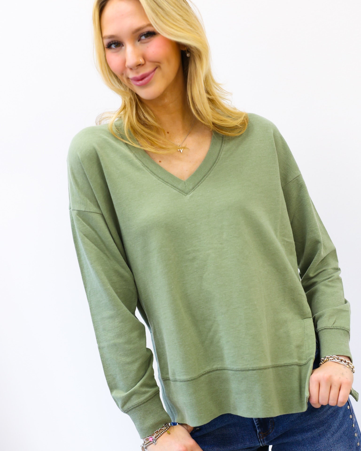 Woman wearing a green sweater and blue jeans on a white background