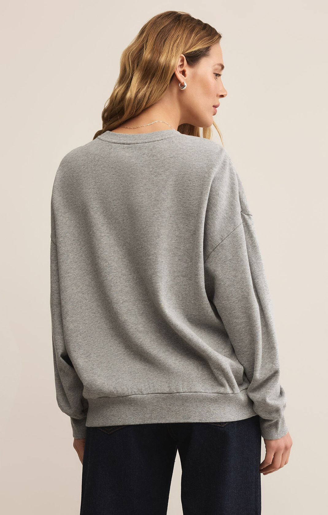 Woman wearing a gray sweater on a beige background