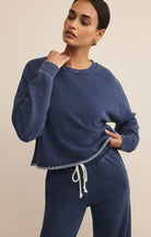 Woman wearing a blue tracksuit against a beige background