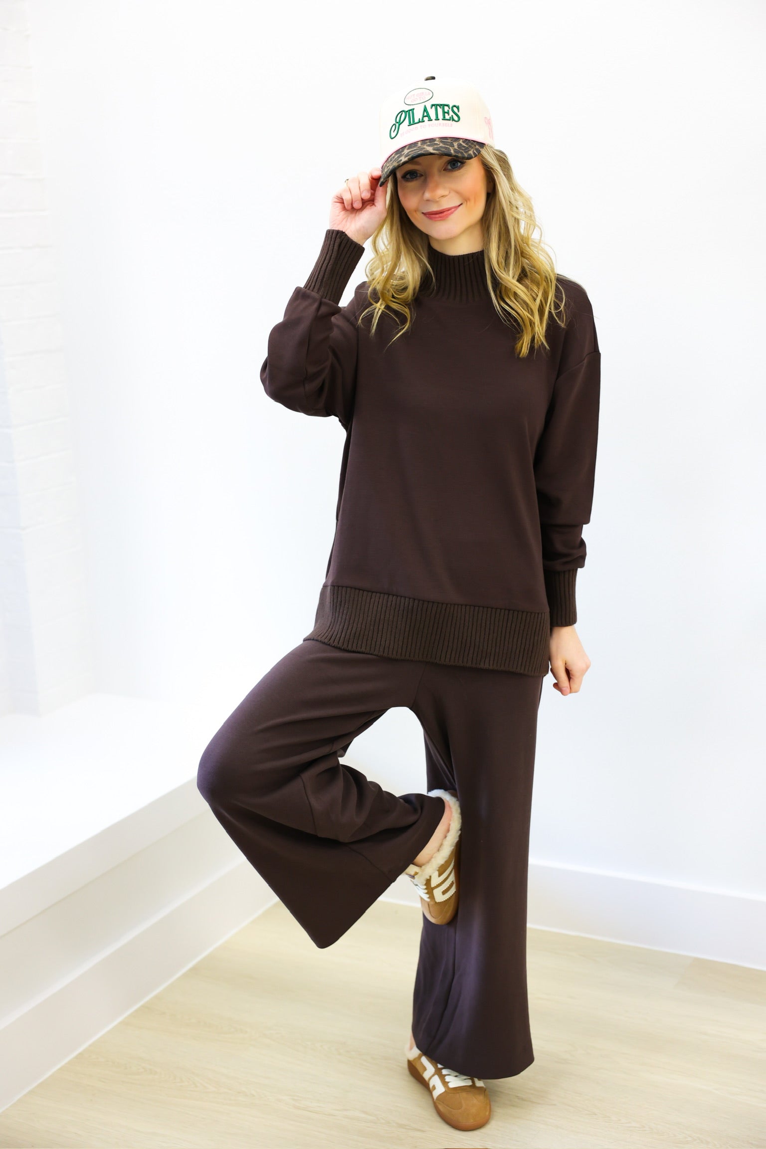 Woman wearing a brown outfit with a white cap indoors